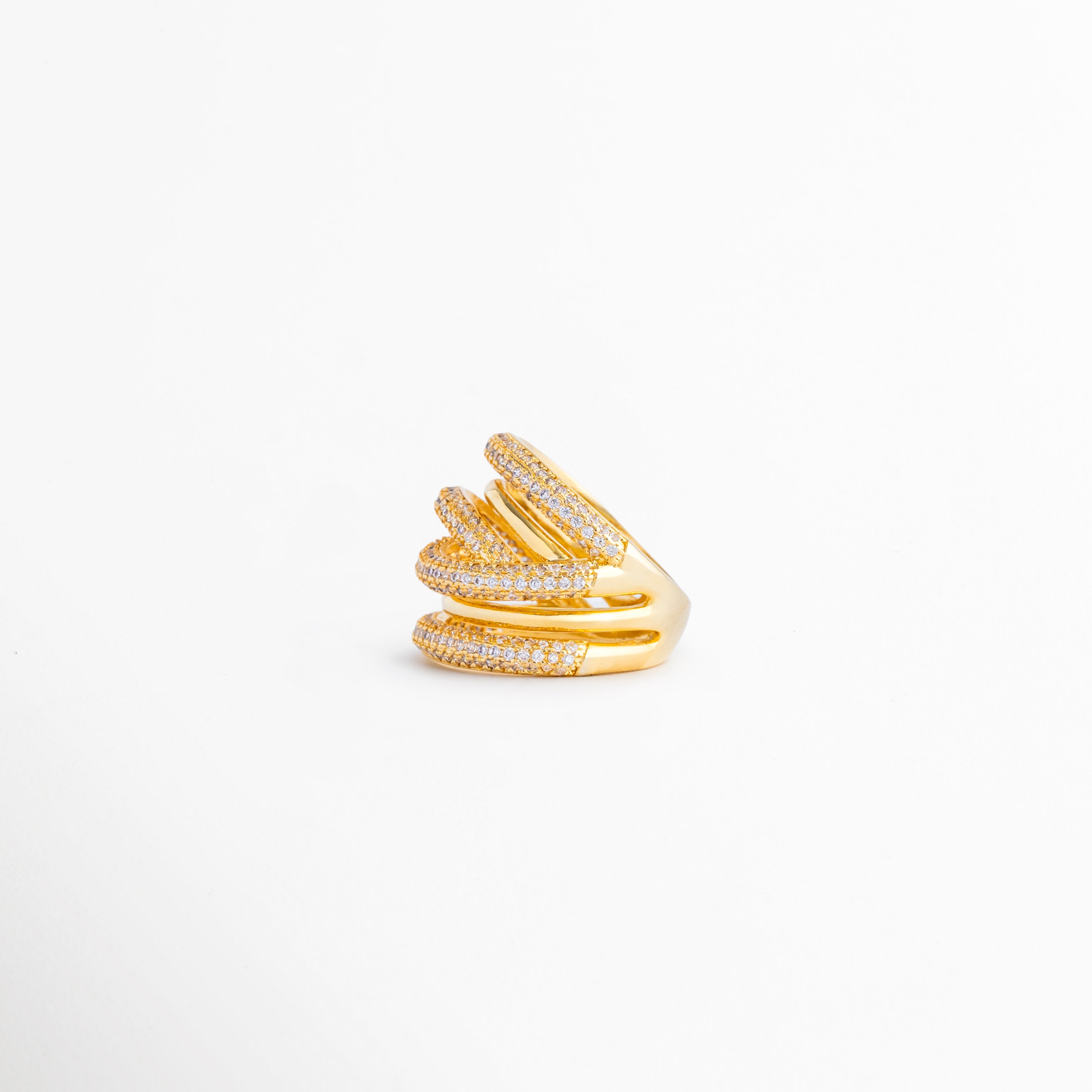 Vista lateral del anillo multicapa que resalta la superposición de bandas y el brillo de las zirconias, Perfil lateral de anillo con diseño envolvente en tonos dorado y plateado, inspirado en tendencias modernas de joyería, Anillo de múltiples aros entrelazados visto de costado, destacando su volumen y acabado premium, Detalle lateral del anillo con incrustaciones de zirconias y combinación de metales para un look sofisticado, Perspectiva lateral que muestra la estructura dinámica y elegante de este anillo 