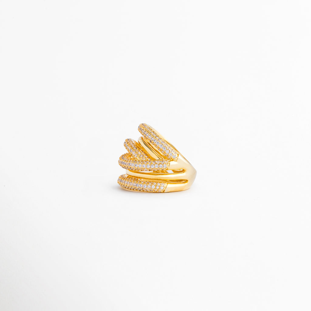 Vista lateral del anillo multicapa que resalta la superposición de bandas y el brillo de las zirconias, Perfil lateral de anillo con diseño envolvente en tonos dorado y plateado, inspirado en tendencias modernas de joyería, Anillo de múltiples aros entrelazados visto de costado, destacando su volumen y acabado premium, Detalle lateral del anillo con incrustaciones de zirconias y combinación de metales para un look sofisticado, Perspectiva lateral que muestra la estructura dinámica y elegante de este anillo 