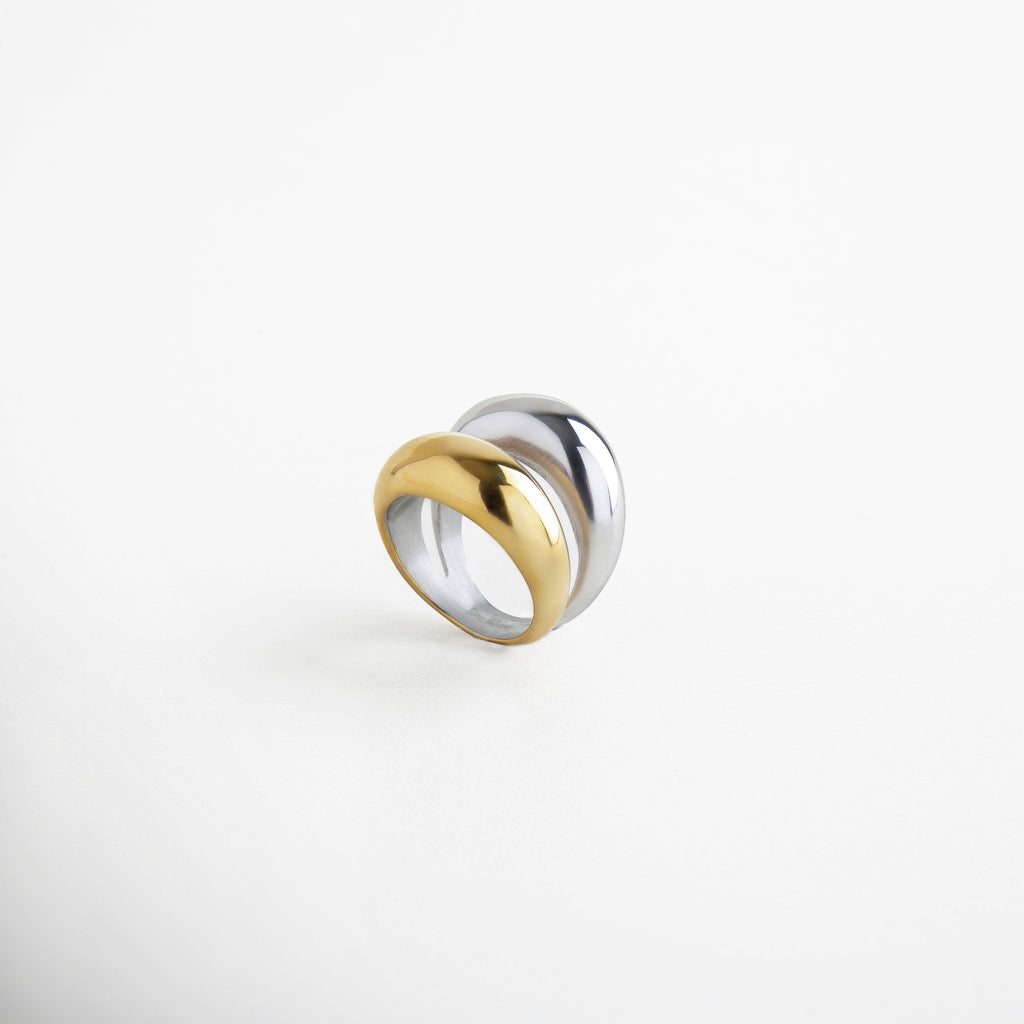 Detalle de anillo doble con acabado dorado y plateado, Textura brillante de anillo bicolor en acero inoxidable, Unión de bandas doradas y plateadas en anillo moderno, Brillo metálico del anillo Doble Bitono