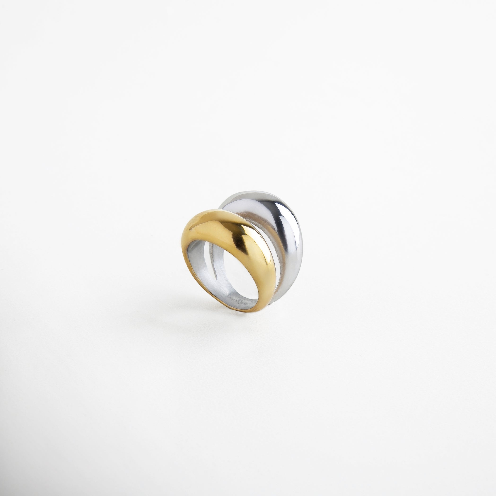 Detalle de anillo doble con acabado dorado y plateado, Textura brillante de anillo bicolor en acero inoxidable, Unión de bandas doradas y plateadas en anillo moderno, Brillo metálico del anillo Doble Bitono