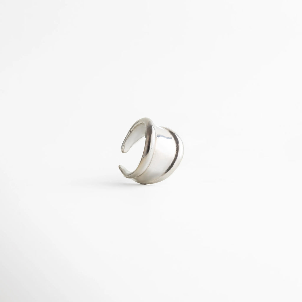 Anillo plateado abierto con acabado pulido, diseño minimalista de líneas envolventes y estética moderna, joyería elegante para mujer.