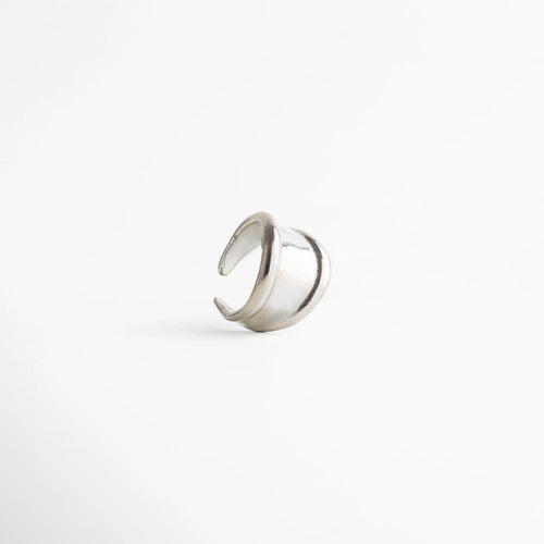 Anillo plateado abierto con acabado pulido, diseño minimalista de líneas envolventes y estética moderna, joyería elegante para mujer.