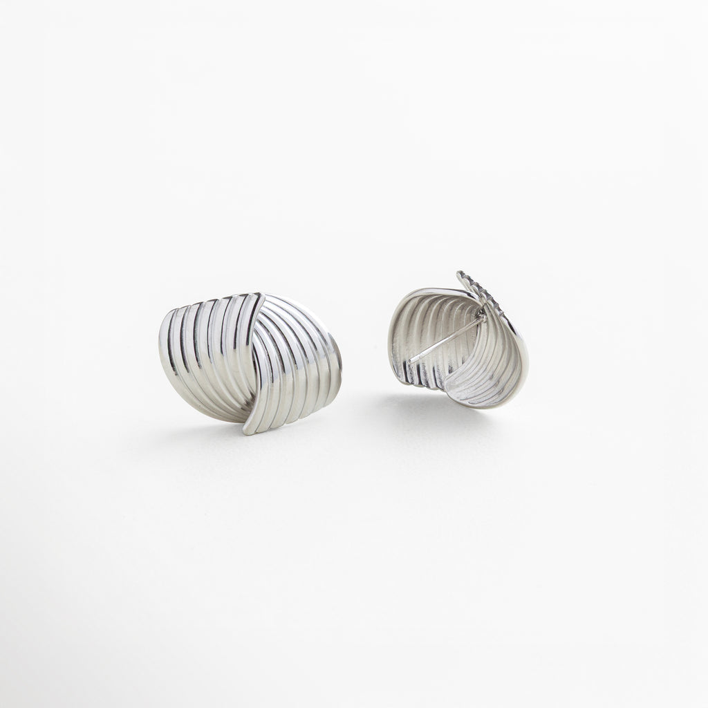 Broche seguro de presión en aretes Ita Silver, fabricados en acero inoxidable 316 con recubrimiento en oro blanco 18K, diseño texturizado y envolvente, comodidad y firmeza para uso diario, joyería elegante y funcional
