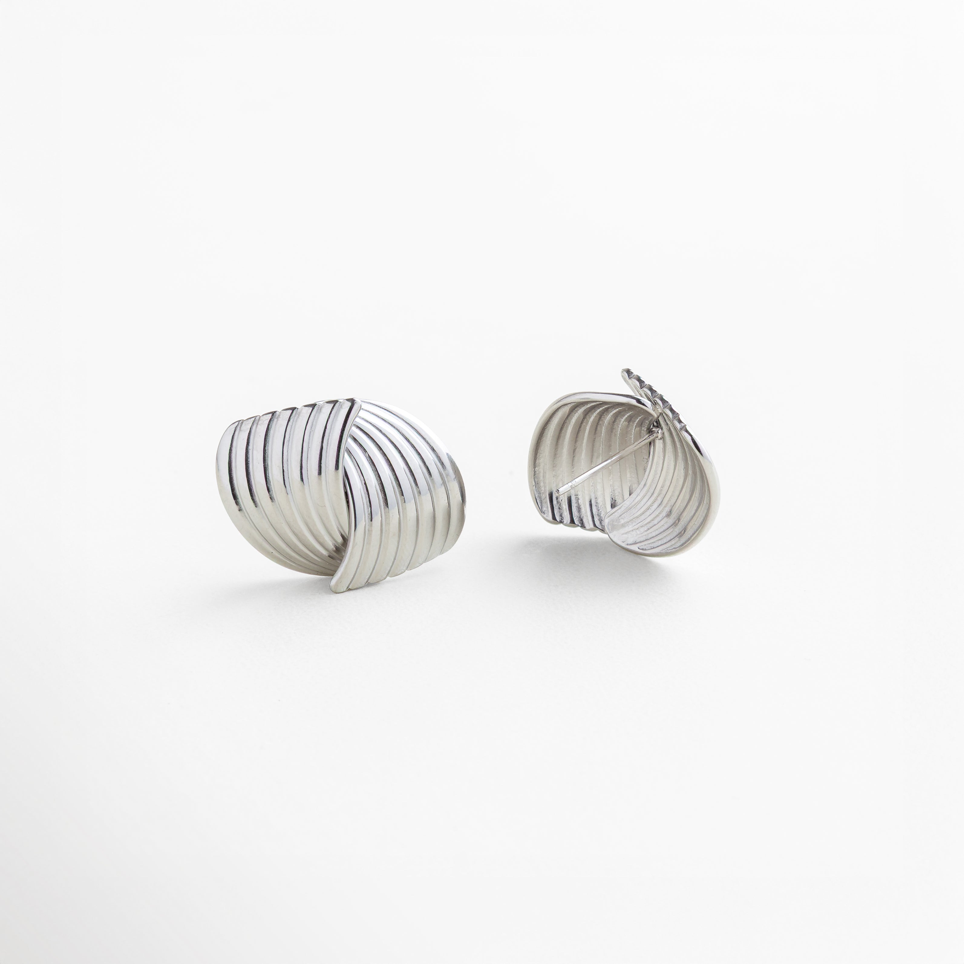 Broche seguro de presión en aretes Ita Silver, fabricados en acero inoxidable 316 con recubrimiento en oro blanco 18K, diseño texturizado y envolvente, comodidad y firmeza para uso diario, joyería elegante y funcional