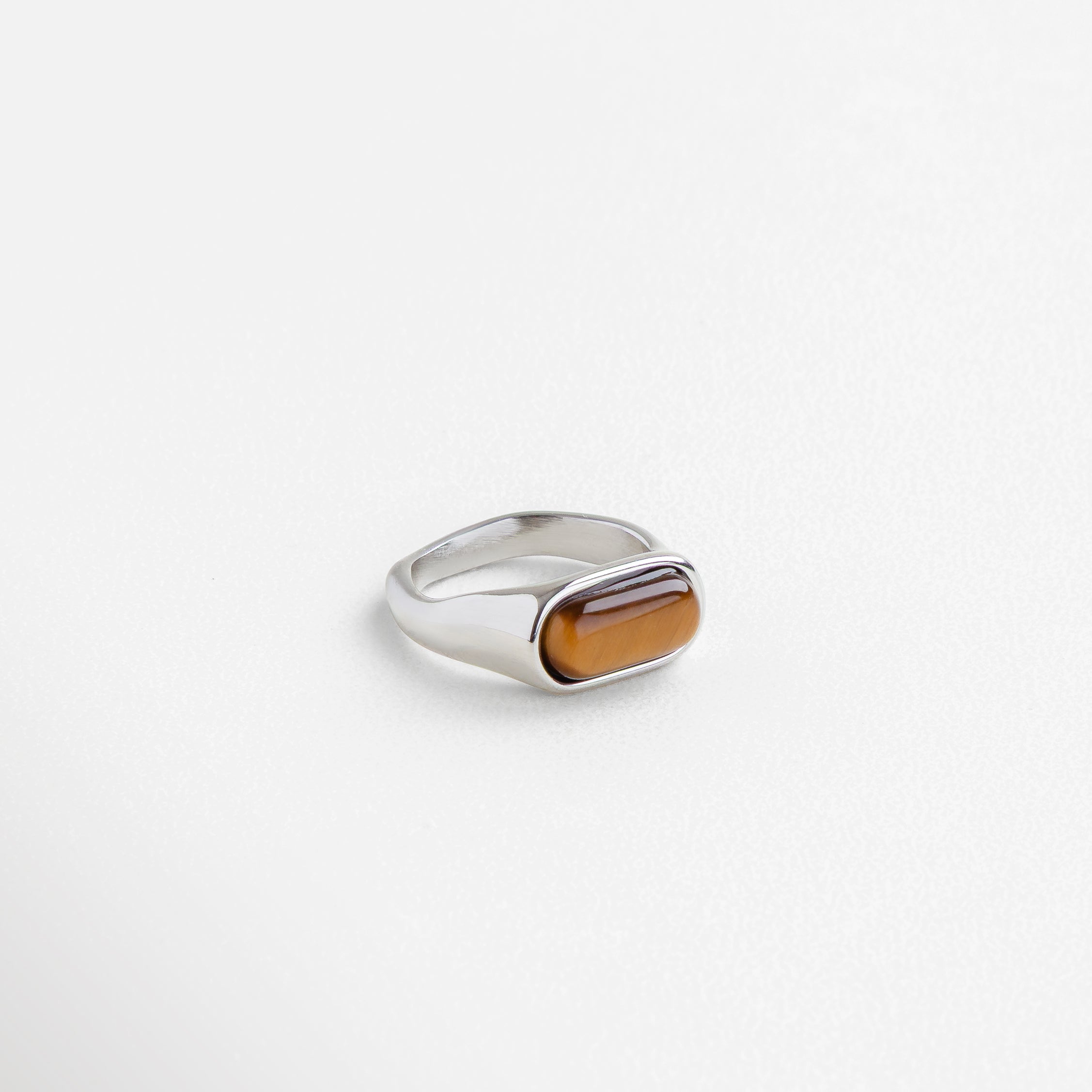 Anillo dorado con piedra ojo de tigre rectangular, Anillo statement dorado con piedra natural marrón, Joya dorada con piedra de ojo de tigre en corte ovalado, Anillo moderno con piedra terrosa en acabado dorado