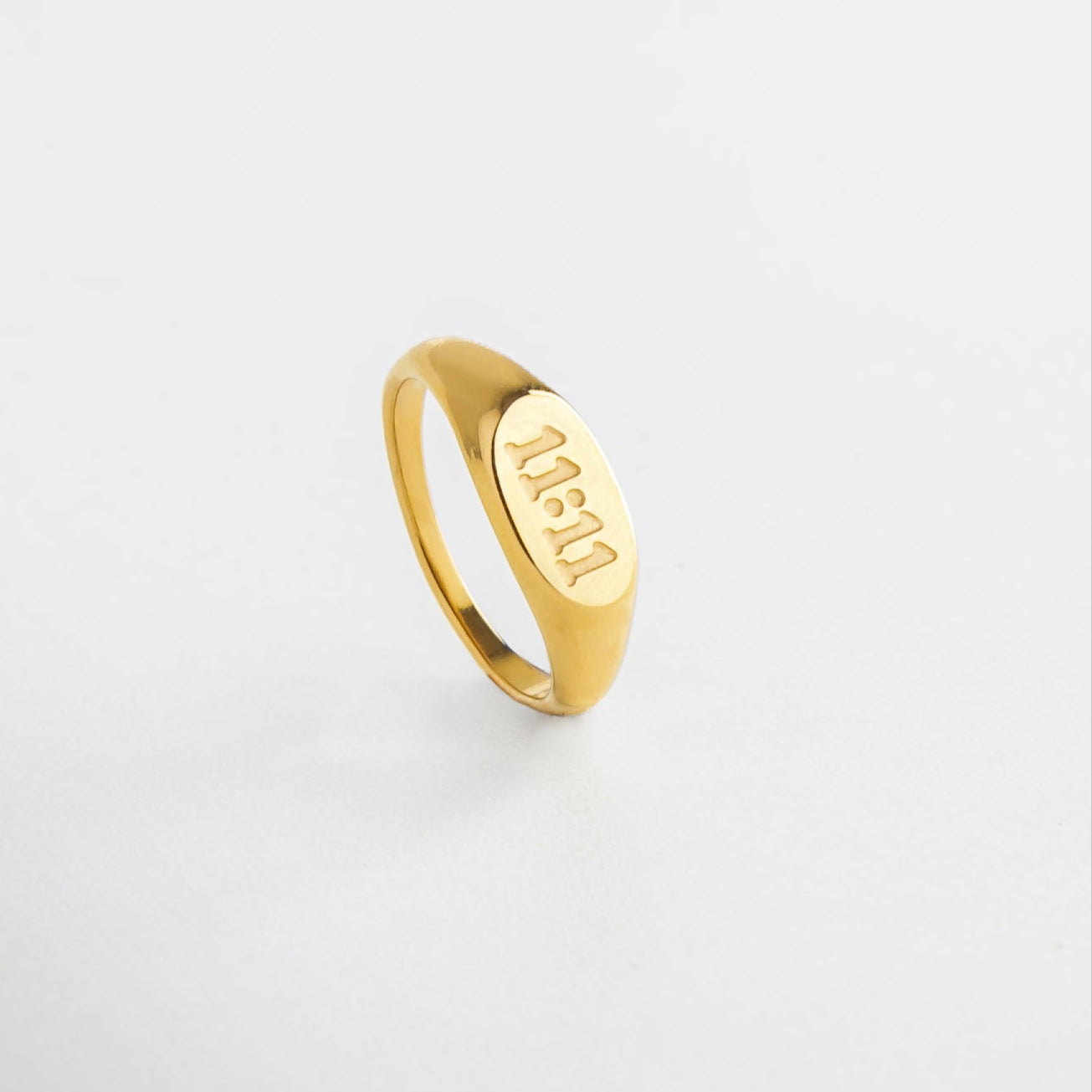 Grabado 11:11 en anillo chapado en oro, Detalle del anillo dorado con inscripción 11:11, Close-up de anillo con grabado simbólico, Textura metálica y grabado espiritual en anillo