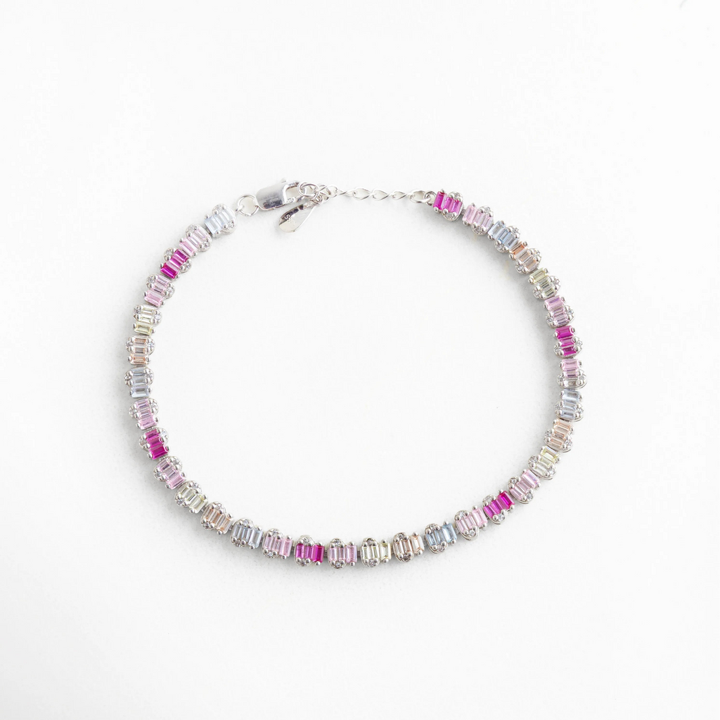 Composición circular de pulsera de plata 925 con baño de oro blanco y piedras de colores, Pulsera completa tipo eternidad con circonias baguette en transición de color fucsia a lila, Brazalete plateado de diseño continuo con cristales brillantes para mujer, Accesorio de muñeca en plata de ley con acabado premium y cristales rectangulares, Vista aérea de pulsera multicolor en oro blanco, ideal para stacking de joyas.