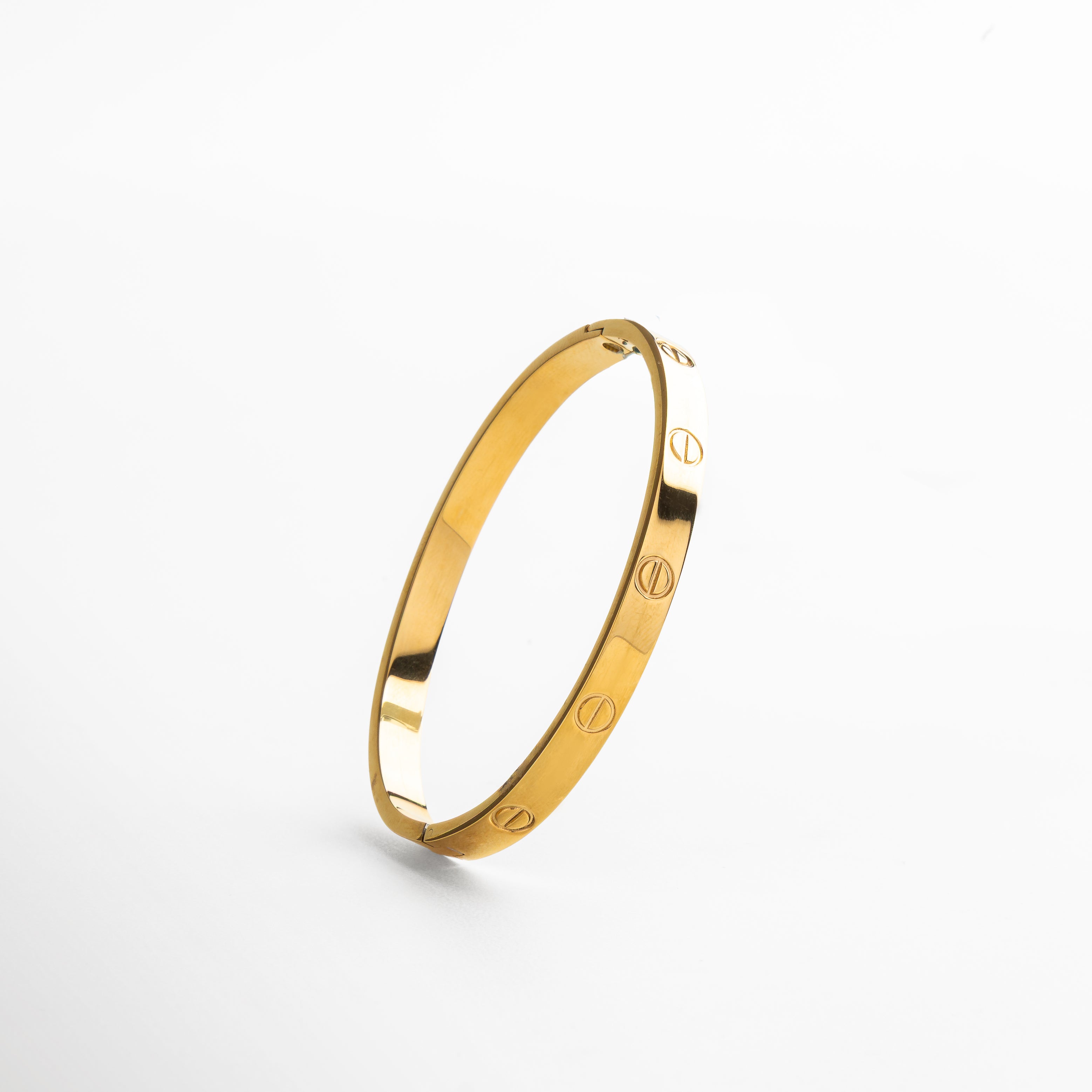 detalle del acabado brillante del brazalete dorado, superficie lisa y pulida en acero de titanio, bordes delgados y minimalistas en brazalete rígido, textura metálica en acabado dorado de alto brillo, enfoque en línea depurada del diseño clásico
