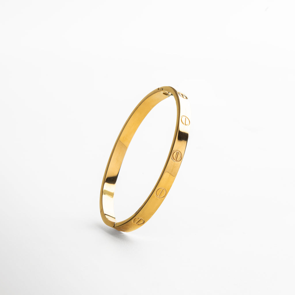 detalle del acabado brillante del brazalete dorado, superficie lisa y pulida en acero de titanio, bordes delgados y minimalistas en brazalete rígido, textura metálica en acabado dorado de alto brillo, enfoque en línea depurada del diseño clásico