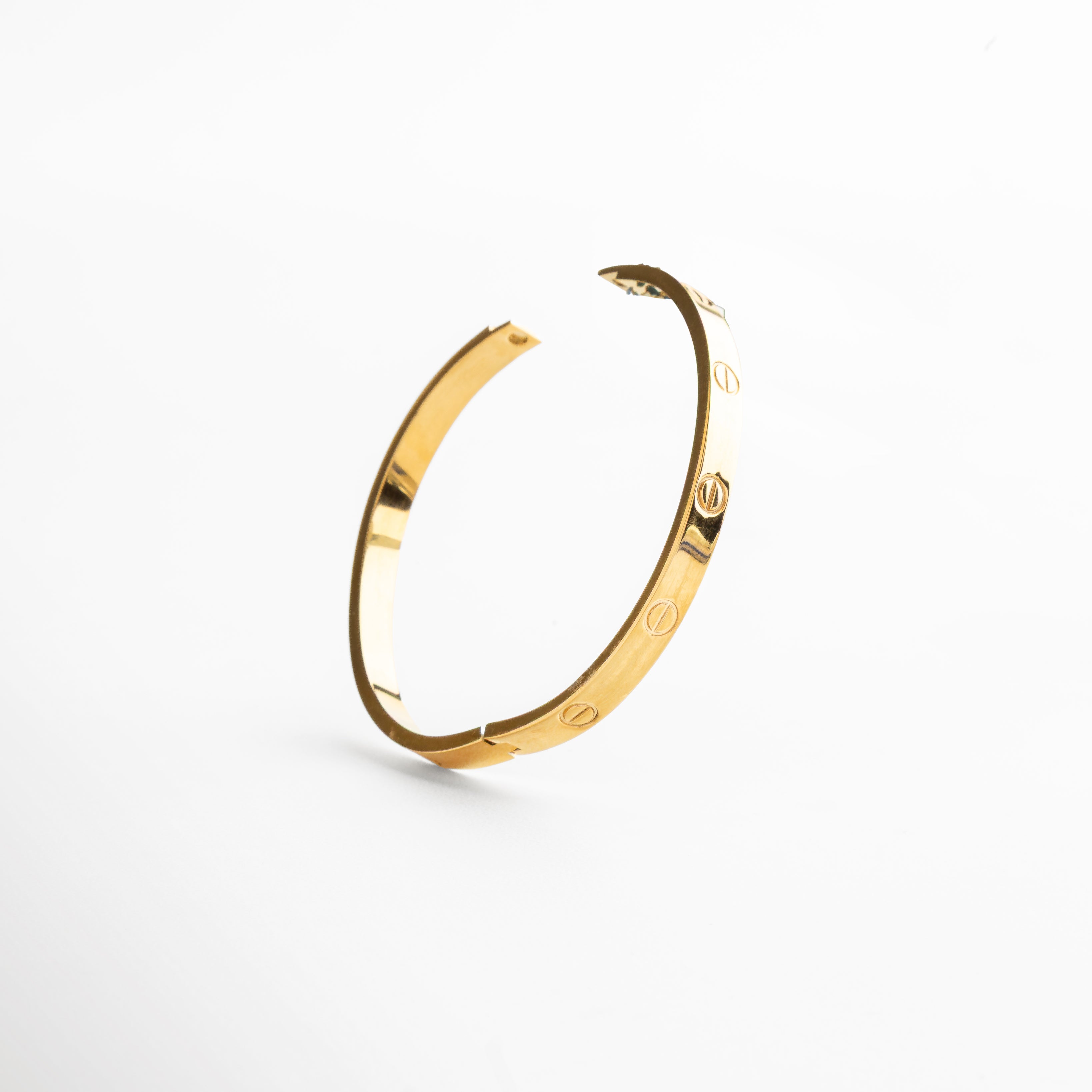 cierre rígido del brazalete dorado, sistema de apertura metálico en oro 18K, detalle del broche estructurado dorado, cierre minimalista en brazalete contemporáneo, mecanismo de ajuste del brazalete rígido dorado