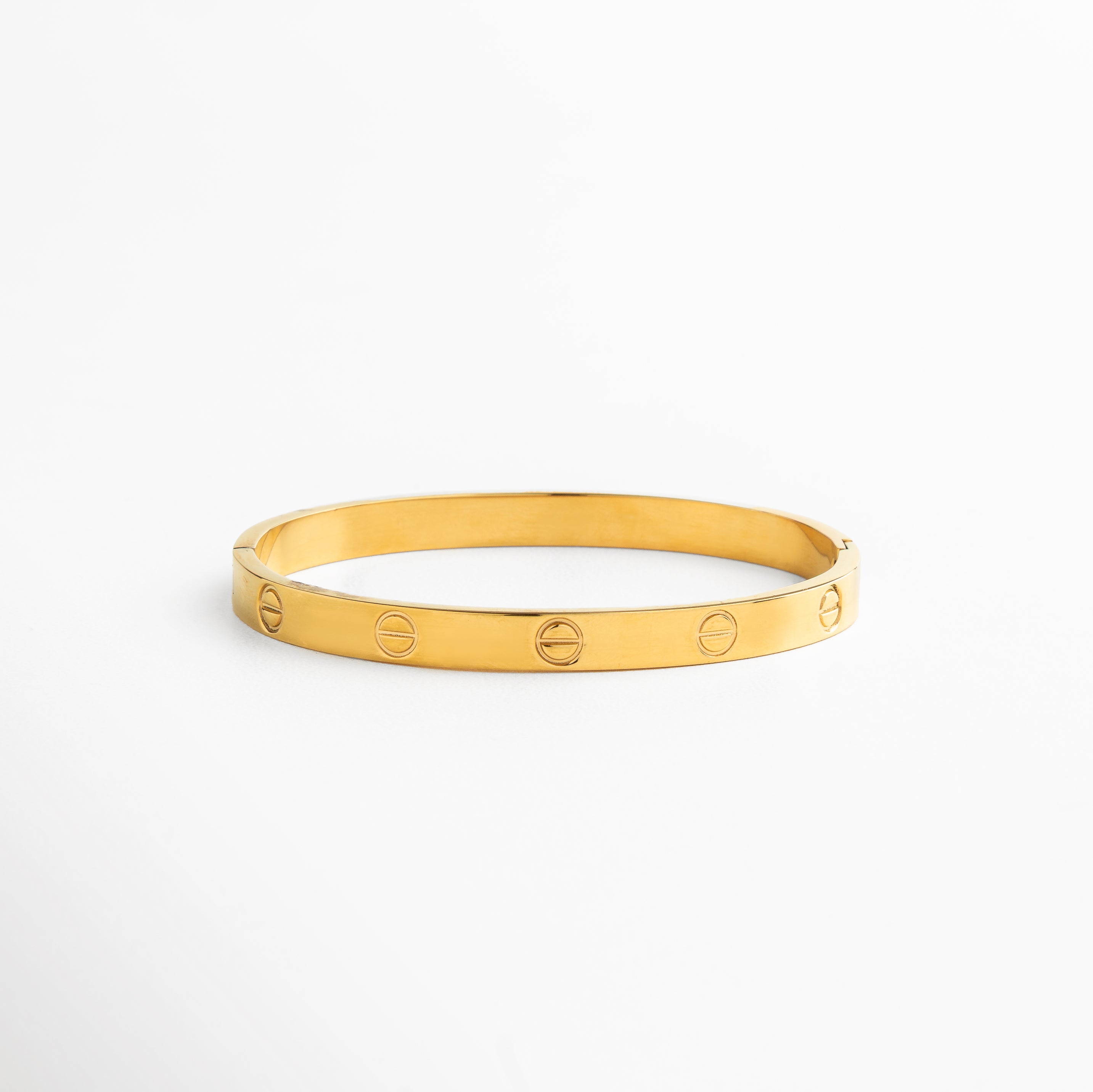 brazalete dorado minimalista de acero de titanio, diseño depurado con acabado pulido en oro amarillo 18K, brazalete rígido dorado de líneas limpias, brazalete contemporáneo y atemporal color dorado, vista frontal de brazalete dorado de 0.5 cm de ancho