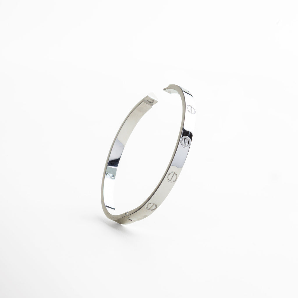 cierre rígido del brazalete en oro blanco 18K, sistema de apertura metálico en brazalete de titanio, detalle del broche estructurado en color plata, cierre minimalista en diseño de brazalete contemporáneo, mecanismo de ajuste del brazalete rígido plateado