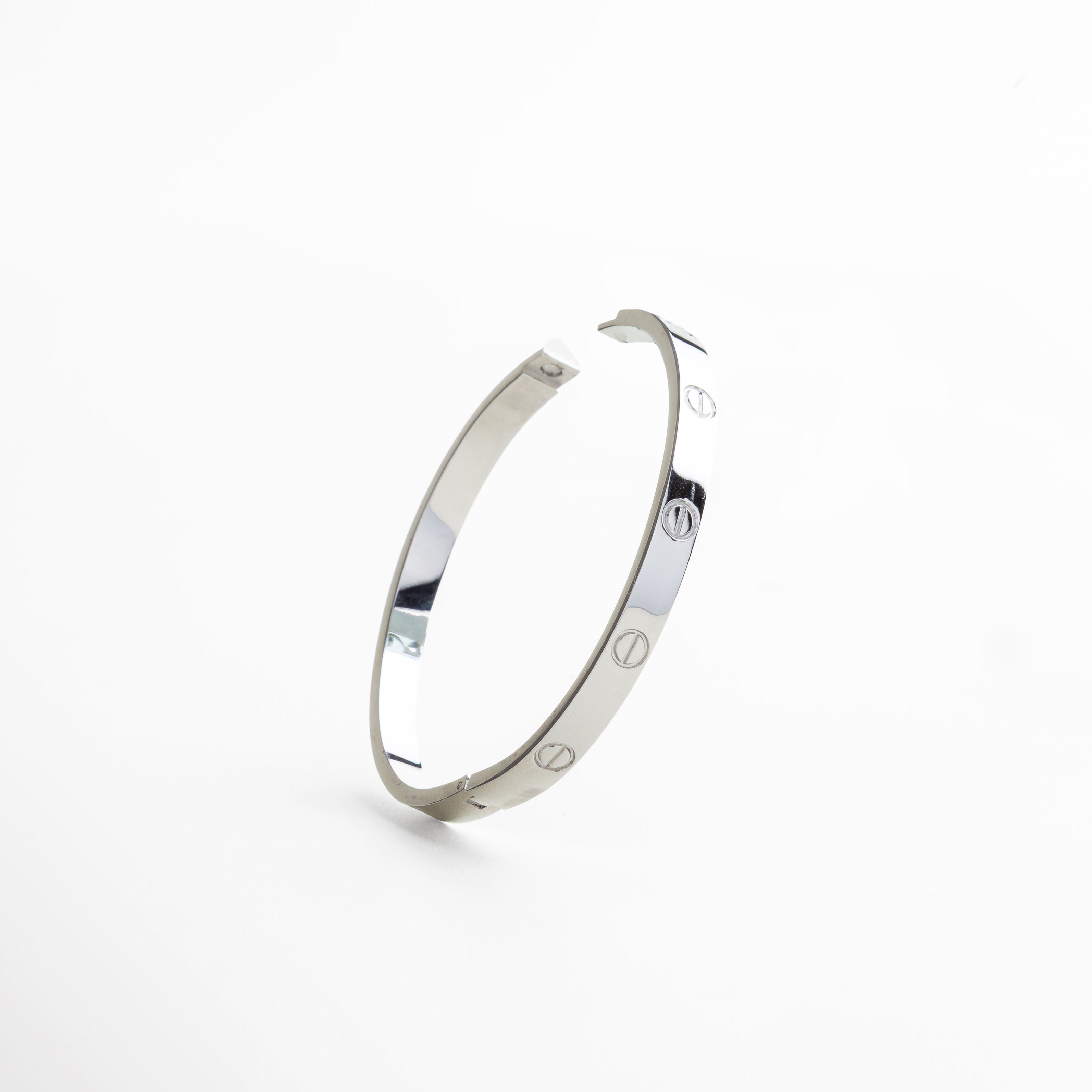 cierre rígido del brazalete en oro blanco 18K, sistema de apertura metálico en brazalete de titanio, detalle del broche estructurado en color plata, cierre minimalista en diseño de brazalete contemporáneo, mecanismo de ajuste del brazalete rígido plateado
