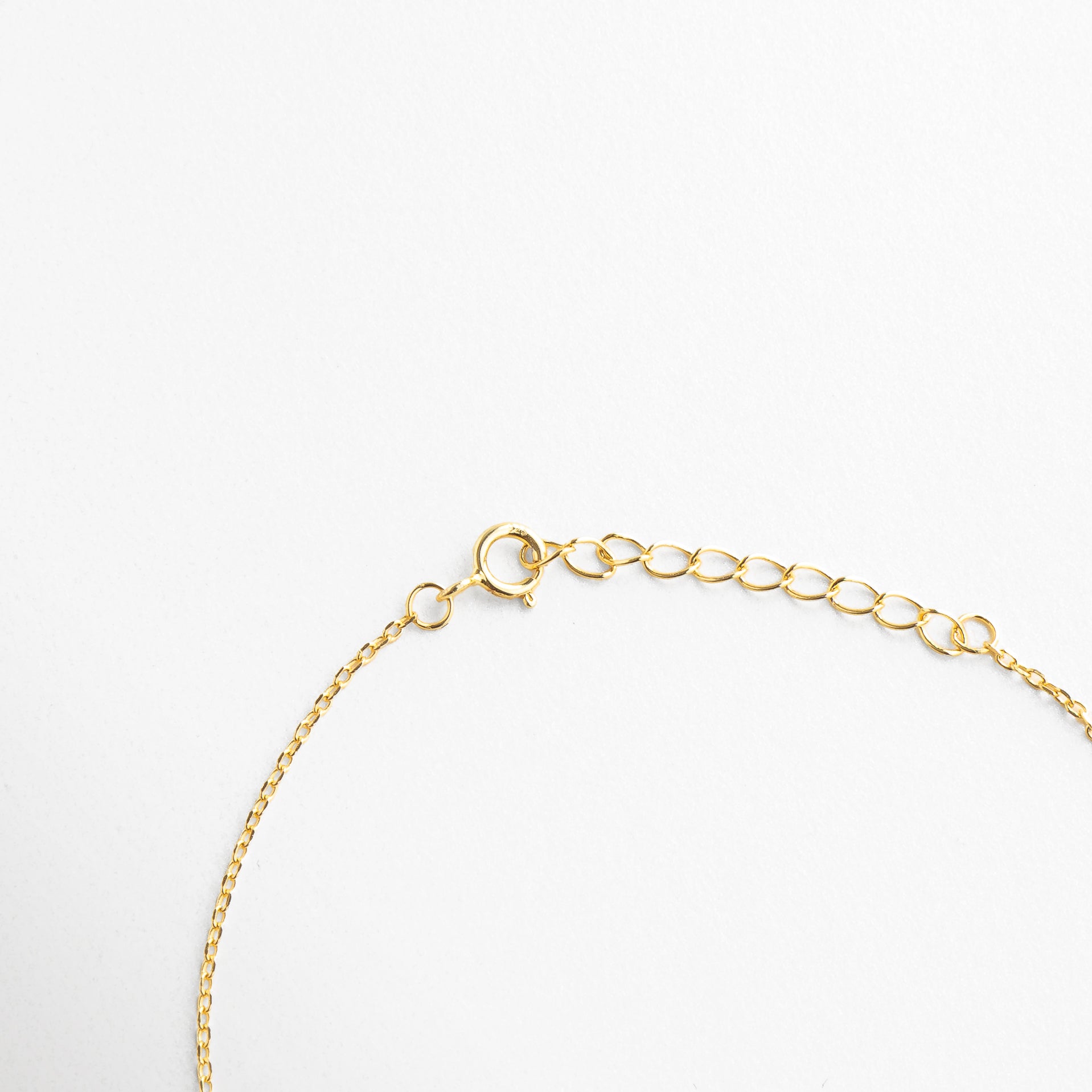 Broche tipo reasa con acabado en oro brillante, Cadena de extensión para ajuste personalizado, Cierre seguro y discreto con eslabones finos, Terminación metálica pulida junto al broche, Sistema de cierre funcional y estético