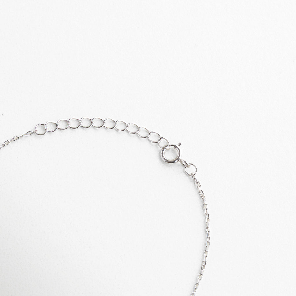 Broche tipo reasa con acabado en plata brillante, Cadena de extensión para ajuste personalizado, Cierre seguro y discreto con eslabones finos, Terminación metálica pulida junto al broche, Sistema de cierre funcional y estético