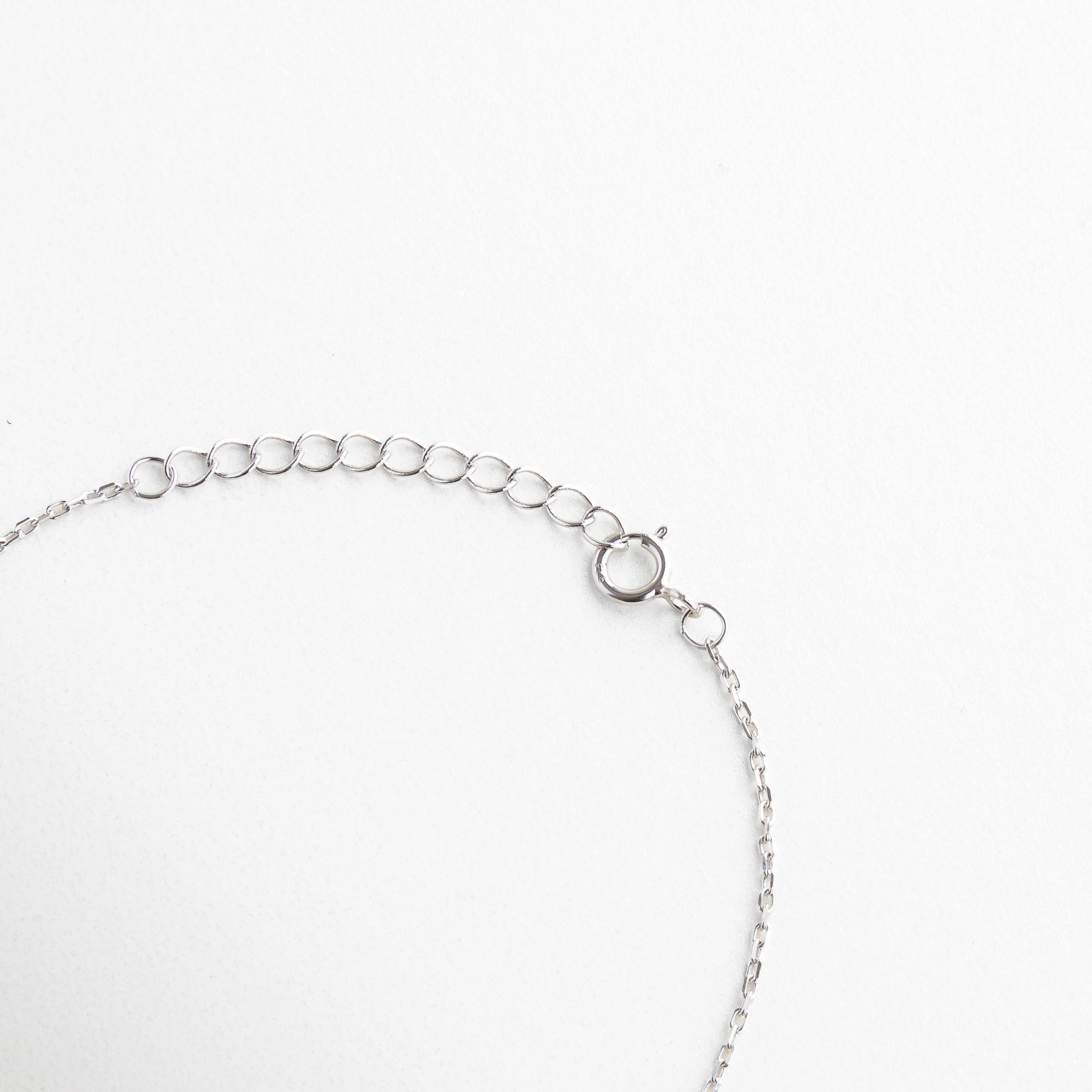 Broche tipo reasa con acabado en plata brillante, Cadena de extensión para ajuste personalizado, Cierre seguro y discreto con eslabones finos, Terminación metálica pulida junto al broche, Sistema de cierre funcional y estético
