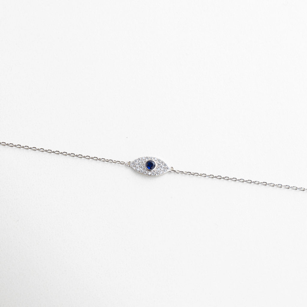 Pulsera plateada con dije de ojo turco y zirconias, Amuleto de protección en diseño moderno y minimalista, Joya simbólica con acabado brillante y sereno, Pulsera en plata ley 925 con toque espiritual, Diseño estilizado con centro de ojo turco brillante