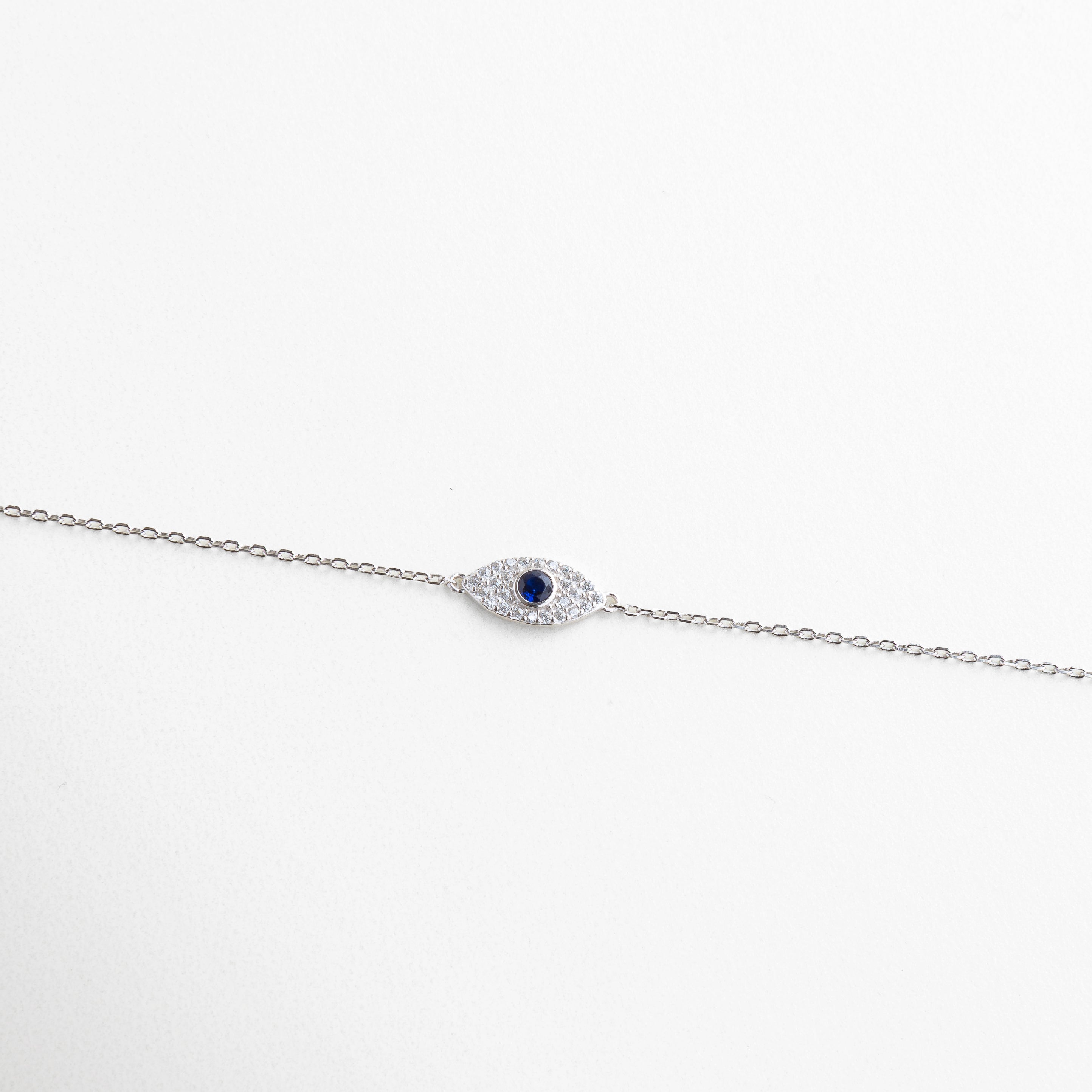Pulsera plateada con dije de ojo turco y zirconias, Amuleto de protección en diseño moderno y minimalista, Joya simbólica con acabado brillante y sereno, Pulsera en plata ley 925 con toque espiritual, Diseño estilizado con centro de ojo turco brillante