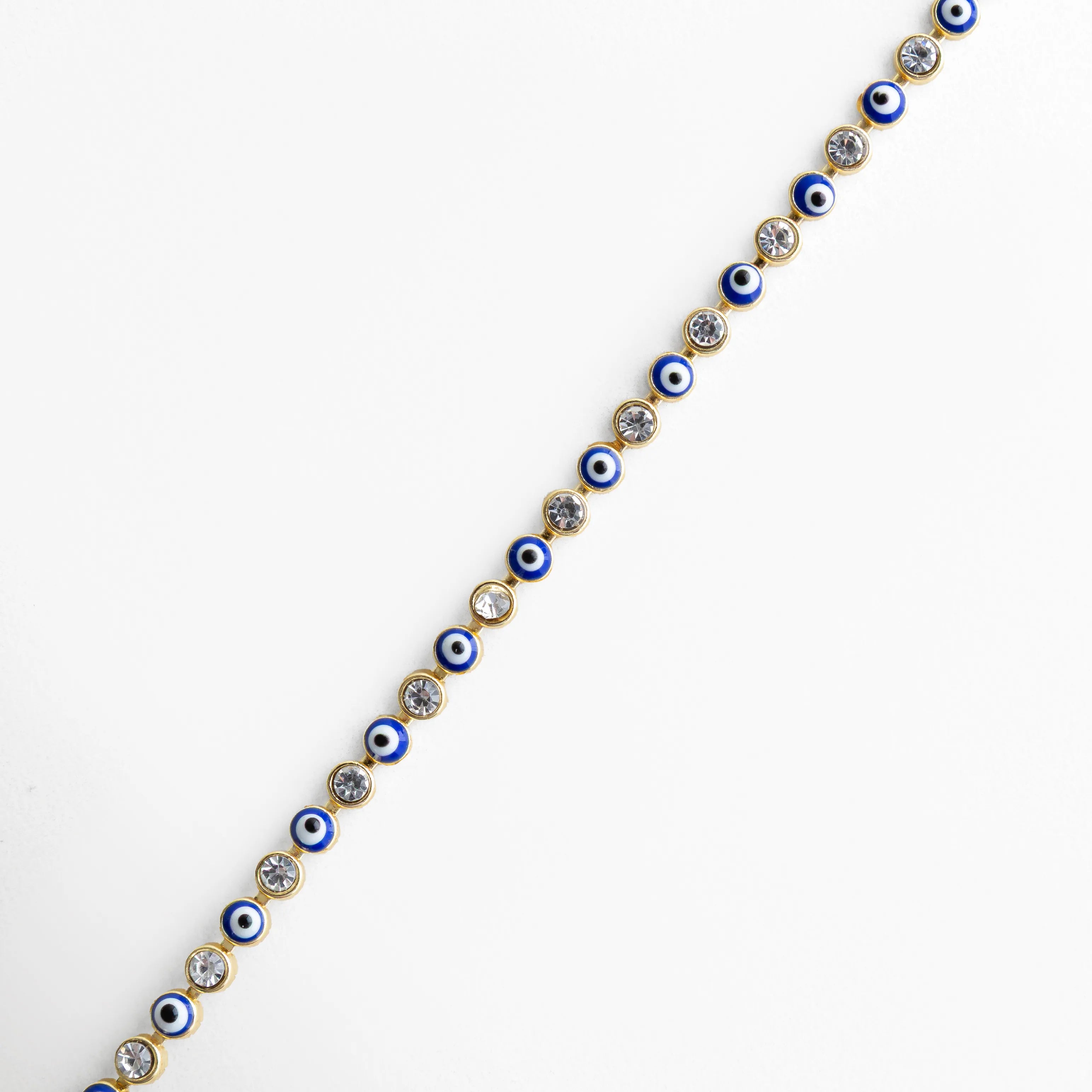 Detalle de pulsera ojitos azul con incrustaciones brillantes y acabado dorado, Primer plano de pulsera con pequeños ojos turcos azules y piedras decorativas, Acercamiento a pulsera dorada con diseño fino y ojitos azules brillantes, Vista lateral de pulsera con patrón de ojos turcos y piedras preciosas artificiales, Detalle elegante de pulsera con acabado enchapado en oro 18K y ojitos azules