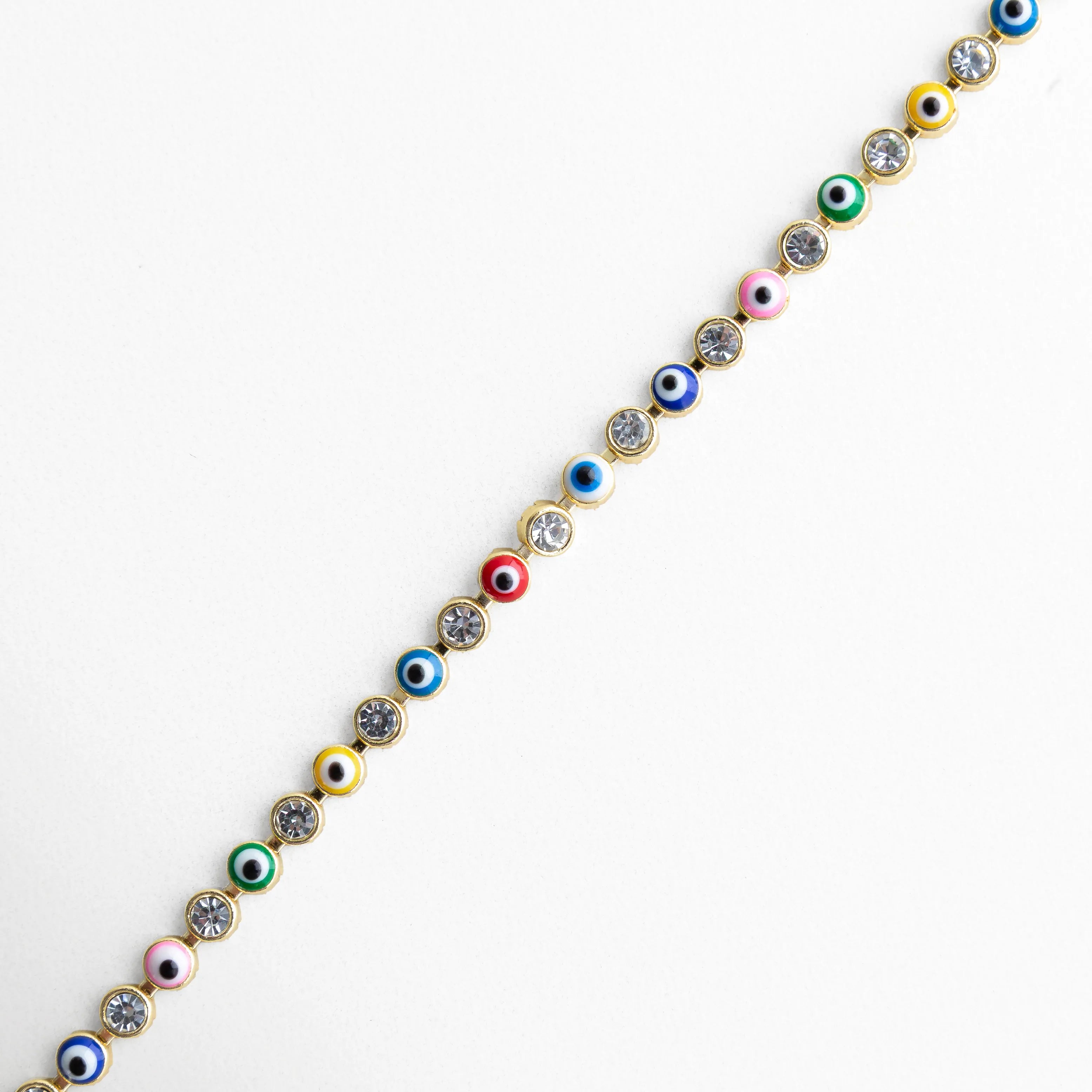 Detalle de pulsera ojitos multicolor con incrustaciones brillantes y acabado dorado, Primer plano de pulsera con pequeños ojos turcos de colores y piedras decorativas, Acercamiento a pulsera dorada con diseño fino y ojitos multicolor, Vista lateral de pulsera con patrón de ojos turcos coloridos y piedras brillantes, Detalle elegante de pulsera con ojitos de colores y acabado enchapado en oro 18K