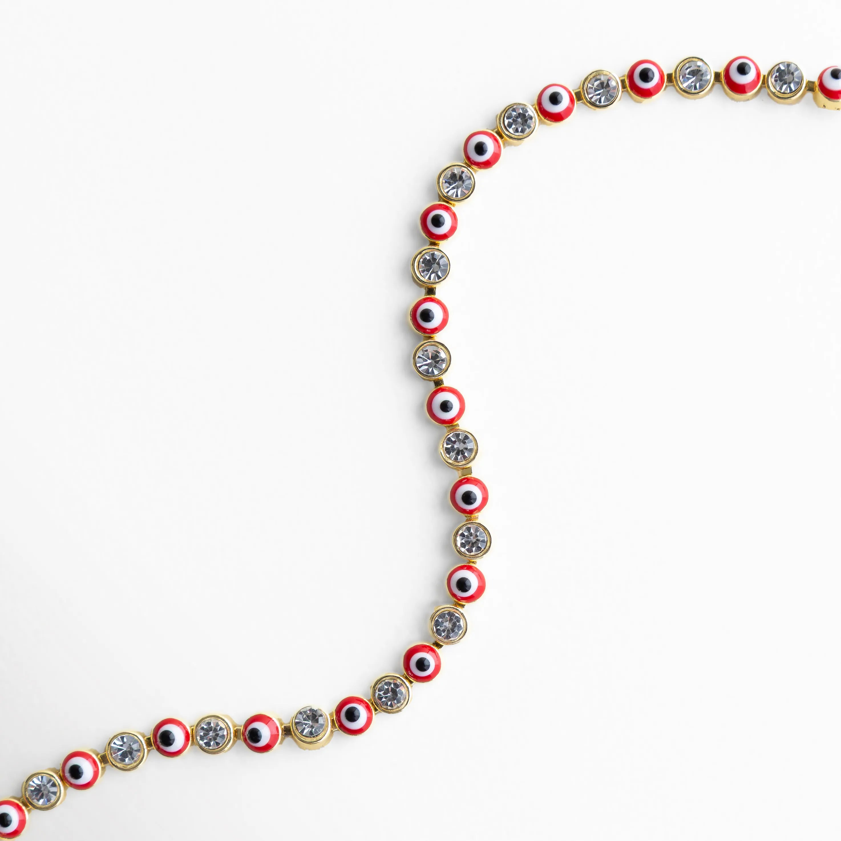 Detalle de pulsera ojitos rojos con incrustaciones brillantes y acabado dorado, Primer plano de pulsera con pequeños ojos turcos rojos y piedras decorativas, Acercamiento a pulsera dorada con diseño fino y ojitos rojos brillantes, Vista lateral de pulsera con patrón de ojos turcos rojos y piedras brillantes, Detalle elegante de pulsera con ojitos rojos y acabado enchapado en oro 18K