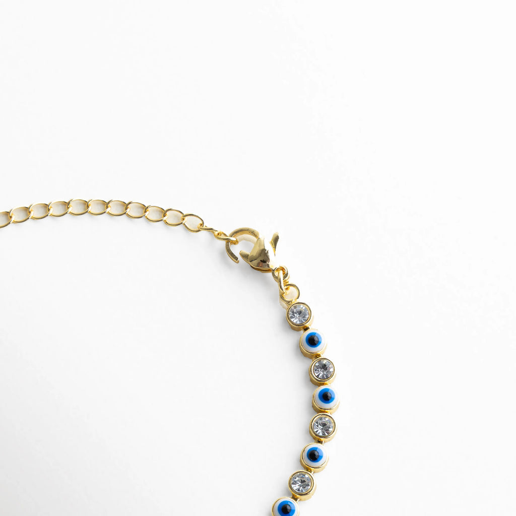 Cadena ajustable de pulsera dorada con ojitos azules y cierre delicado, Detalle del broche y extensión de pulsera con diseño fino y elegante, Vista de la estructura de la pulsera con eslabones dorados y piedras azules, Pulsera ajustable con cadena dorada y pequeños ojos turcos distribuidos, Segmento de pulsera con patrón continuo de ojitos azules y acabado brillante