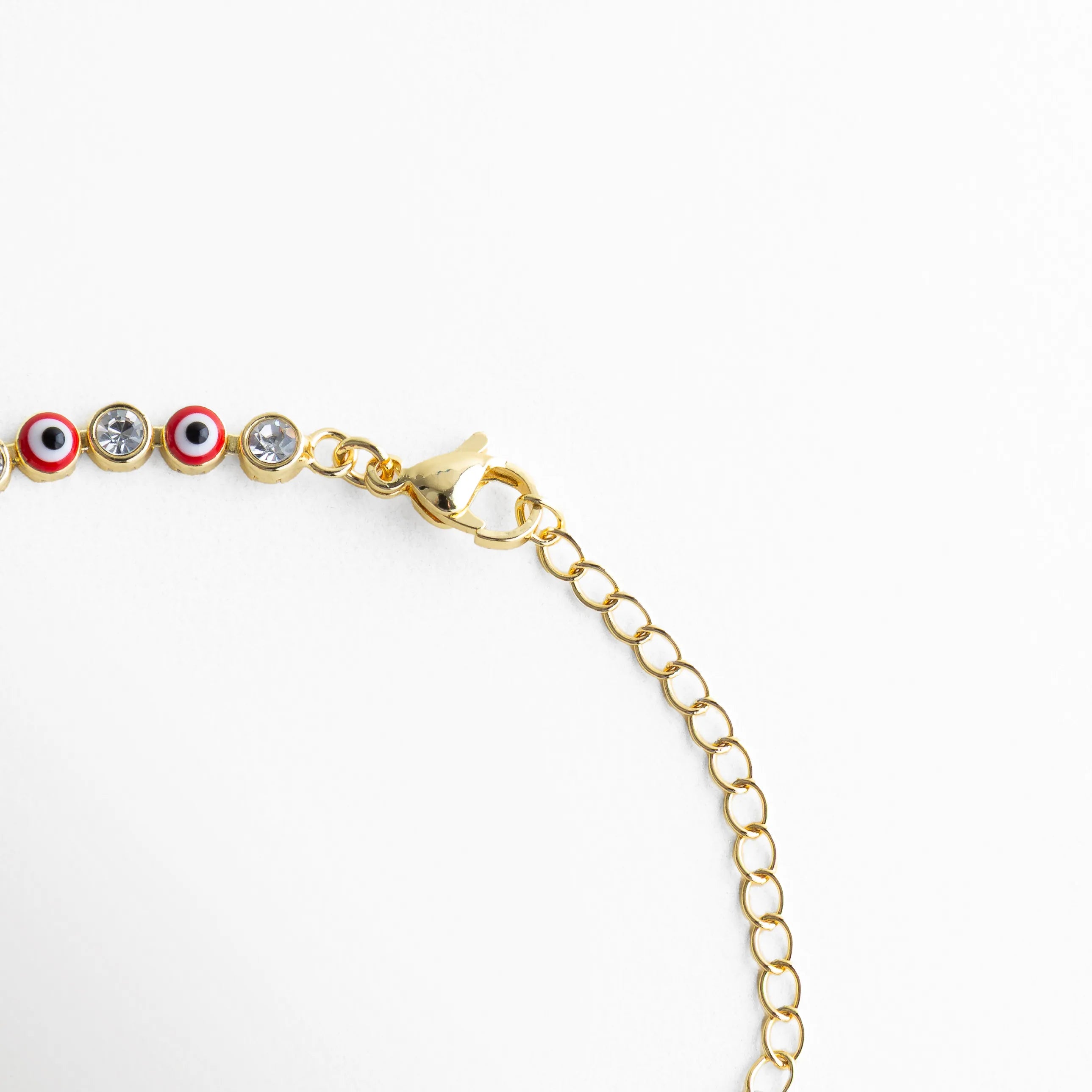 Cadena ajustable de pulsera dorada con ojitos rojos y cierre delicado, Detalle del broche y extensión de pulsera con diseño fino y elegante, Vista de la estructura de pulsera con eslabones dorados y piedras rojas, Pulsera ajustable con cadena dorada y ojos turcos rojos distribuidos, Segmento de pulsera con patrón continuo de ojitos rojos y acabado brillante