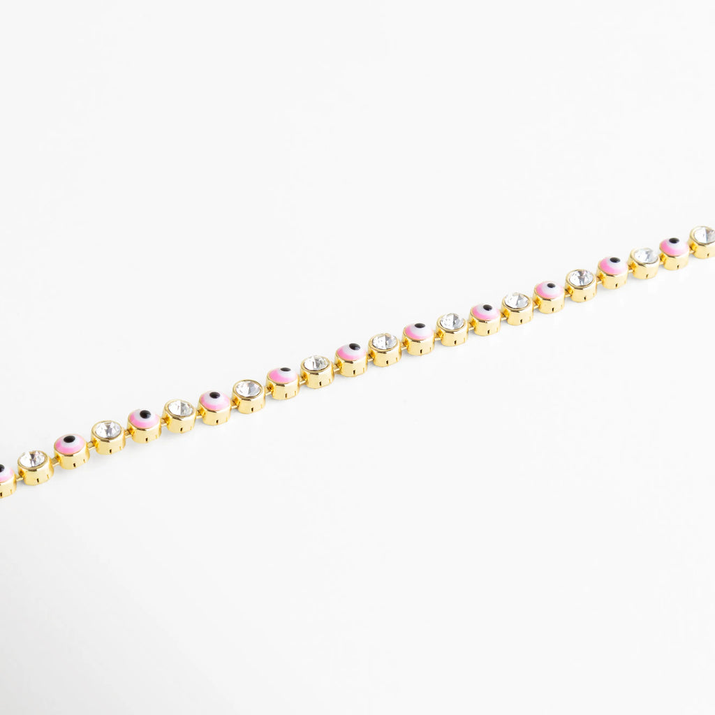 Pulsera dorada decorada con charms de ojito rosa y cristales transparentes, una pieza divertida y protectora.