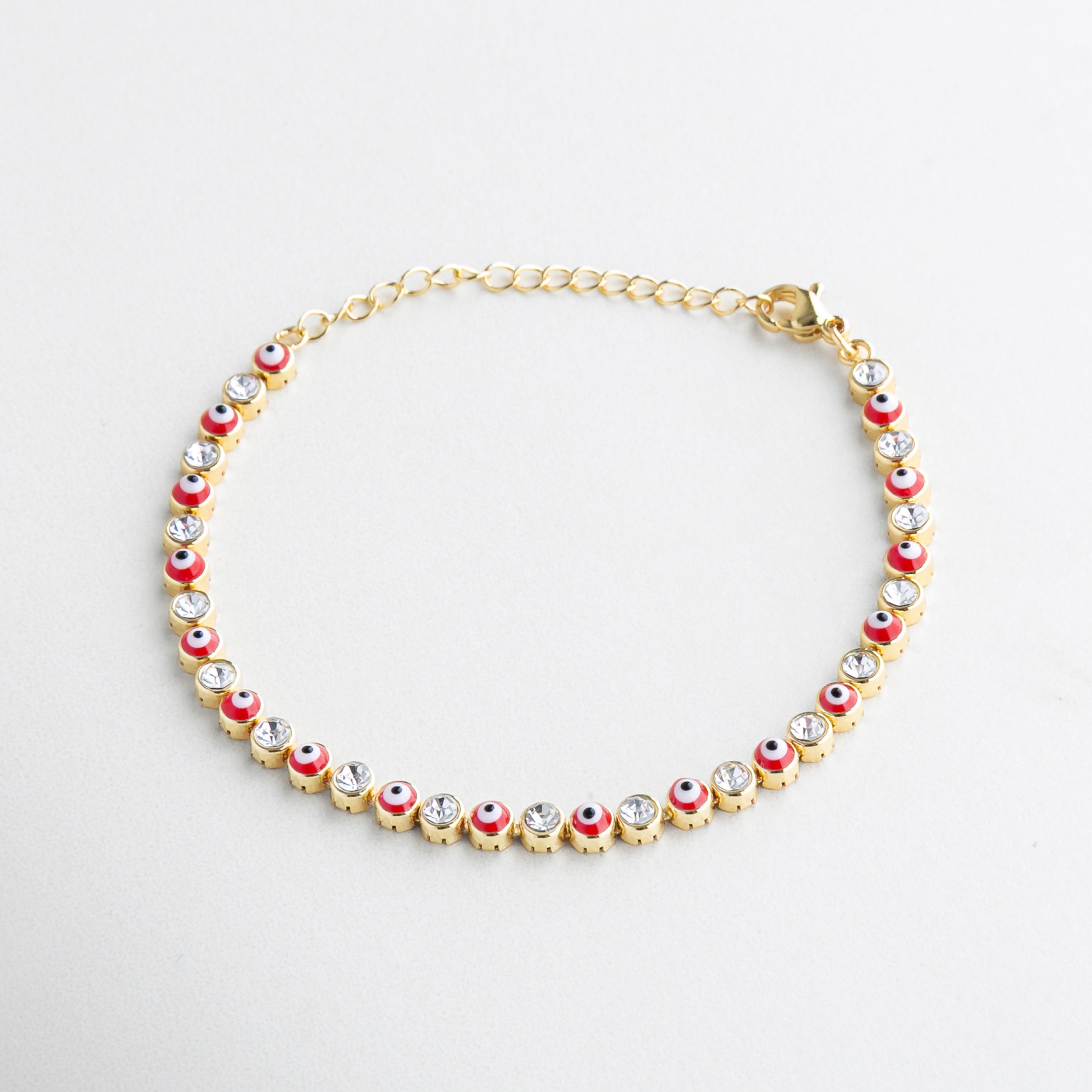 Pulsera roja con dijes de ojos turcos y zirconias, Diseño vibrante con detalles protectores en dorado, Pulsera fina de ojitos con incrustaciones brillantes, Joya con charms simbólicos y estilo moderno, Pulsera de hilo rojo con acentos dorados
