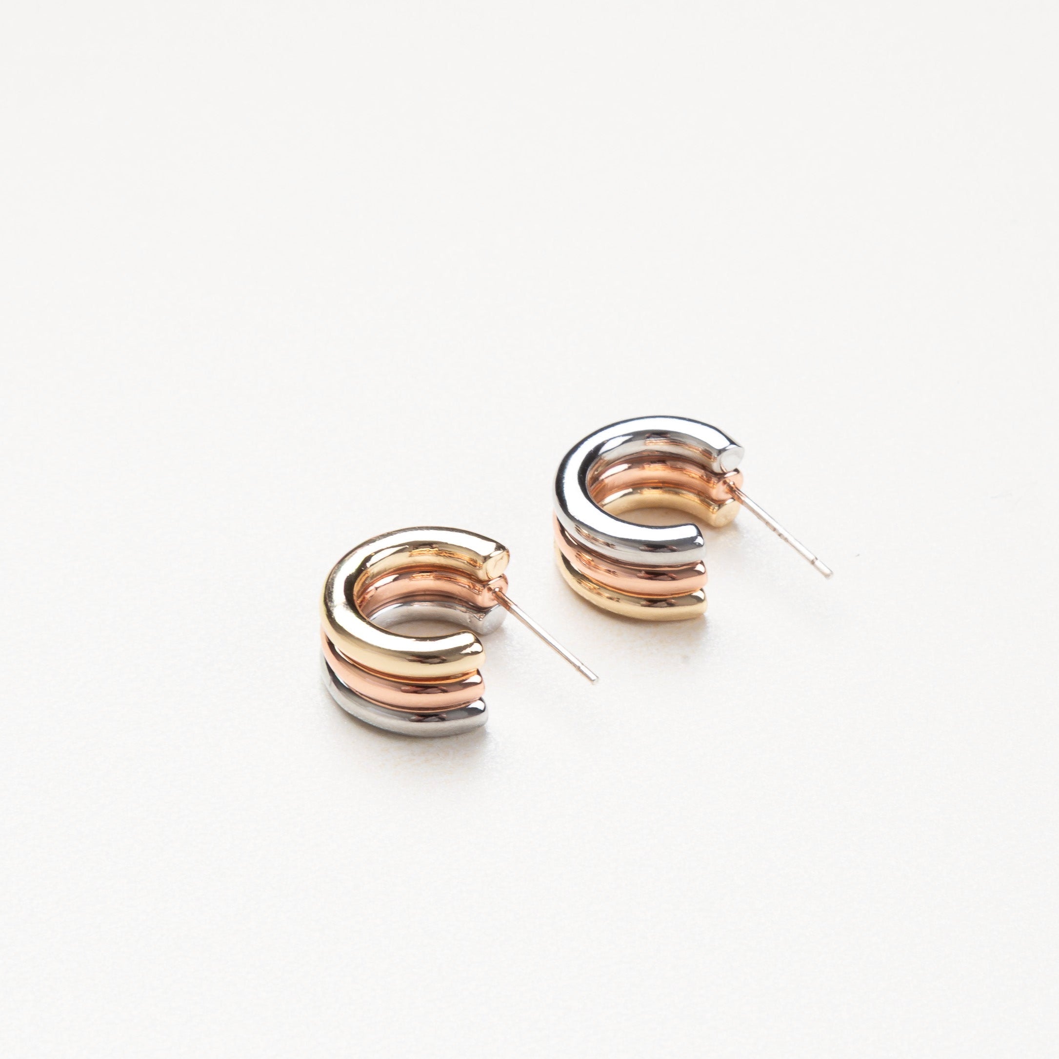 diseño geométrico en plata, pendientes pequeños con gran estilo, aretes modernos de líneas limpias, joyas tricolores para mujer