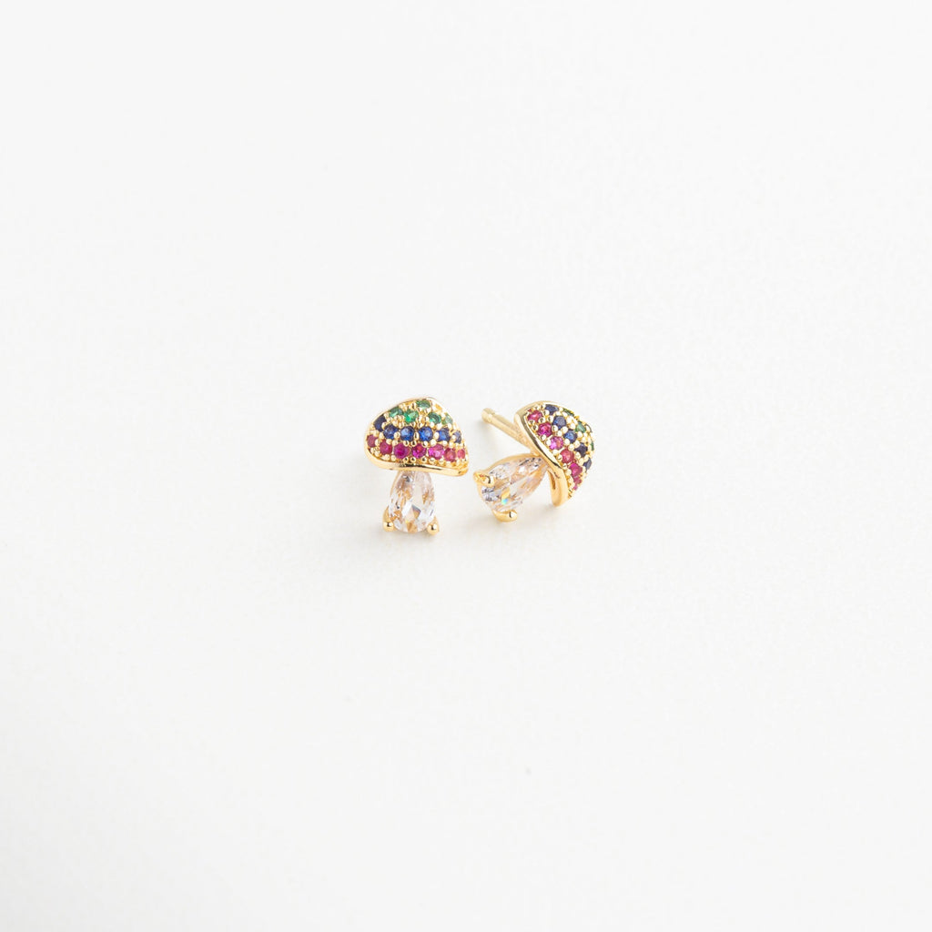 Aretes de hongo dorado vistos en ángulo con brillo sutil, Diseño divertido de pendientes con forma de seta desde el lateral, Aretes chapados en oro con silueta de hongo y colores, Pendientes de honguito dorado con toque delicado