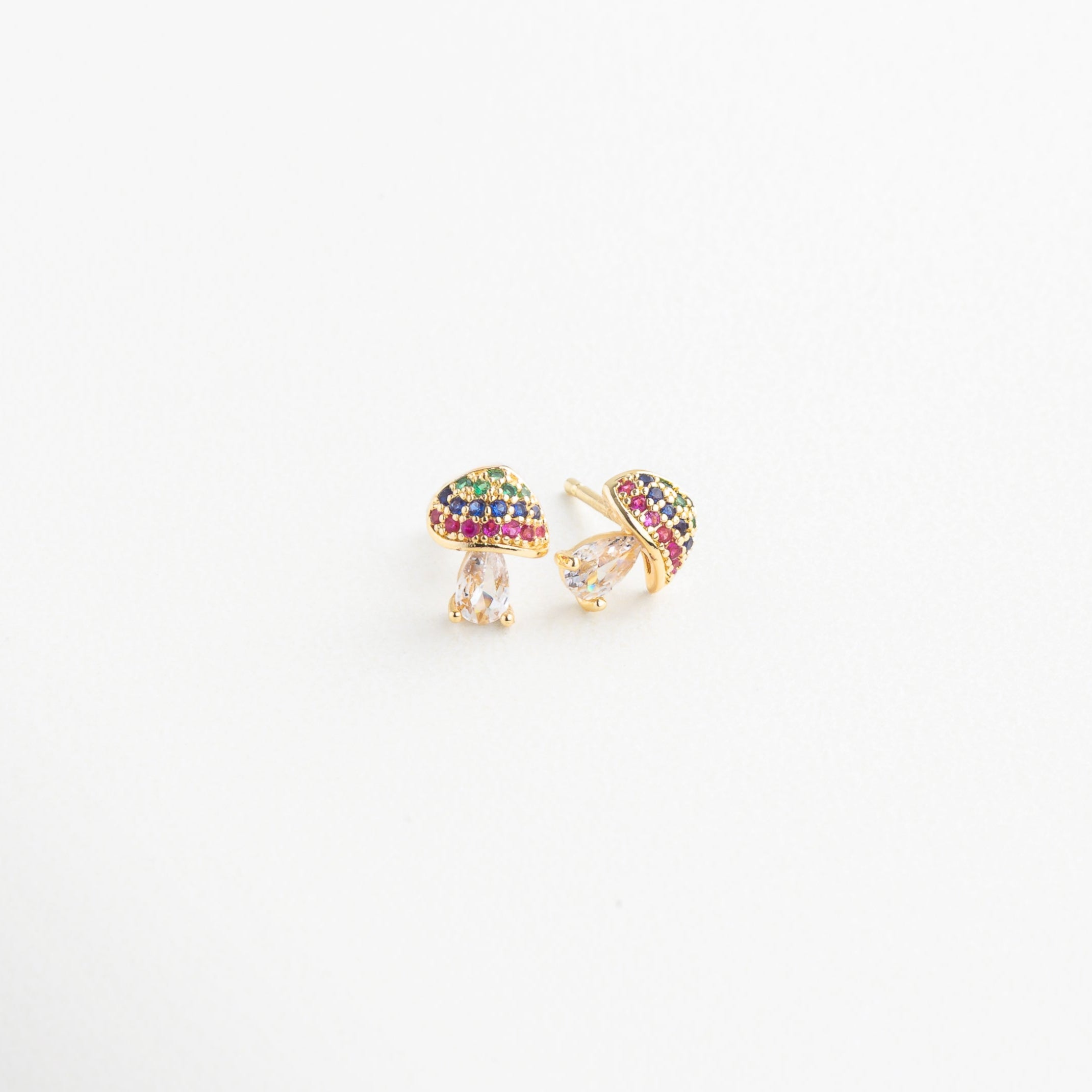 Aretes de hongo dorado vistos en ángulo con brillo sutil, Diseño divertido de pendientes con forma de seta desde el lateral, Aretes chapados en oro con silueta de hongo y colores, Pendientes de honguito dorado con toque delicado