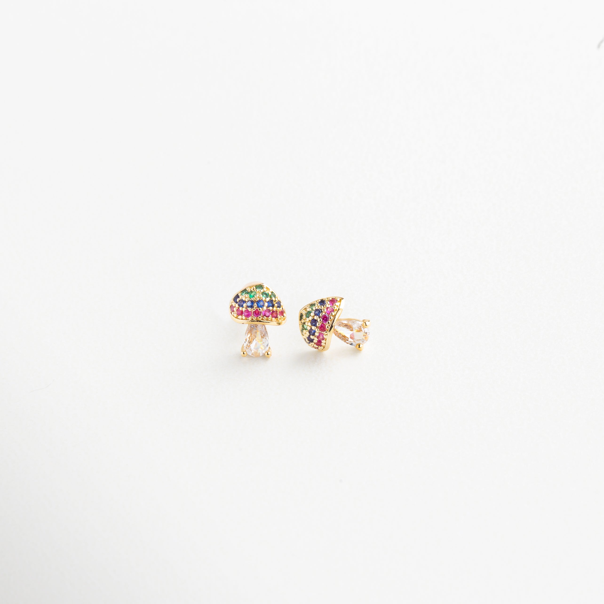 Detalle del diseño de hongo dorado con piedras coloridas, Primer plano de aretes con forma de seta y brillo multicolor, Textura y acabado dorado de pendientes con zirconias, Close-up de los aretes con diseño natural y vibrante