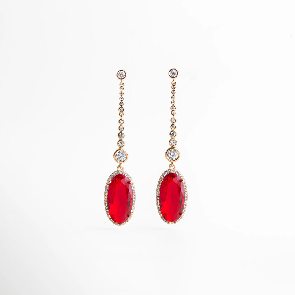 aretes largos dorados con piedra roja ovalada colgante, cadena de zirconias, vista frontal sobre fondo blanco, elegante y brillante, joyería fina para eventos