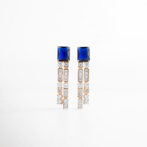 Aretes colgantes plateados con detalles dorados en las esquinas y piedra preciosa en la parte superior, vistos de frente. Vista frontal de aretes elegantes combinando plata y dorado, con piedra brillante en la parte superior. Aretes plateados con colgante y detalles dorados, fotografía frontal completa sobre fondo neutro. Primer plano frontal de los aretes colgantes, mostrando la piedra superior y los detalles dorados. Par de aretes plateados con esquinas doradas y piedra superior, vistos de frente con 
