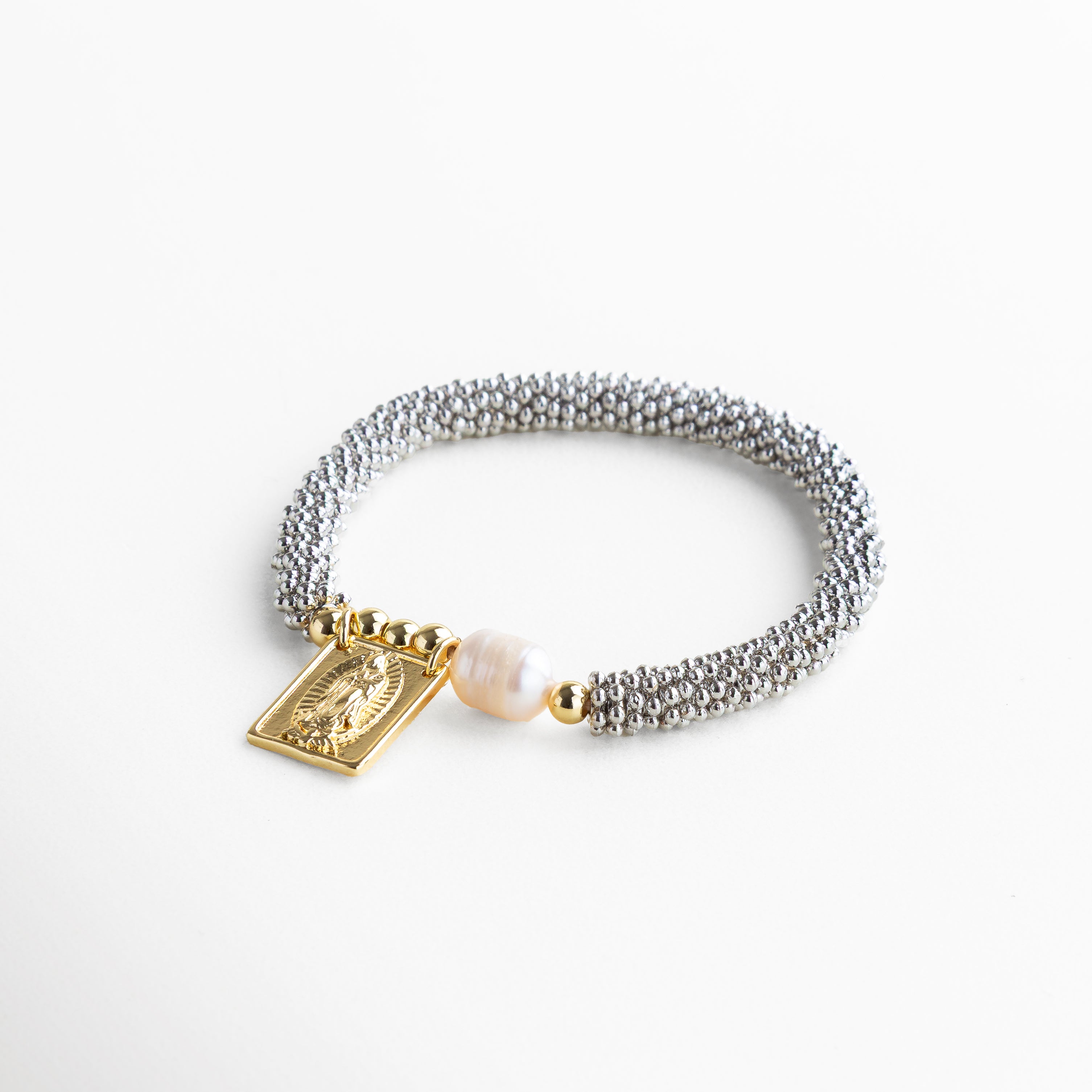 Perfil delgado que permite un uso cómodo y discreto, Pulsera flexible que se ajusta fácilmente a diferentes tamaños de muñeca, Acabado brillante que refleja la luz con sutileza desde todos los ángulos, Estructura resistente que mantiene su forma con el uso diario, Diseño equilibrado entre símbolo religioso y estética moderna