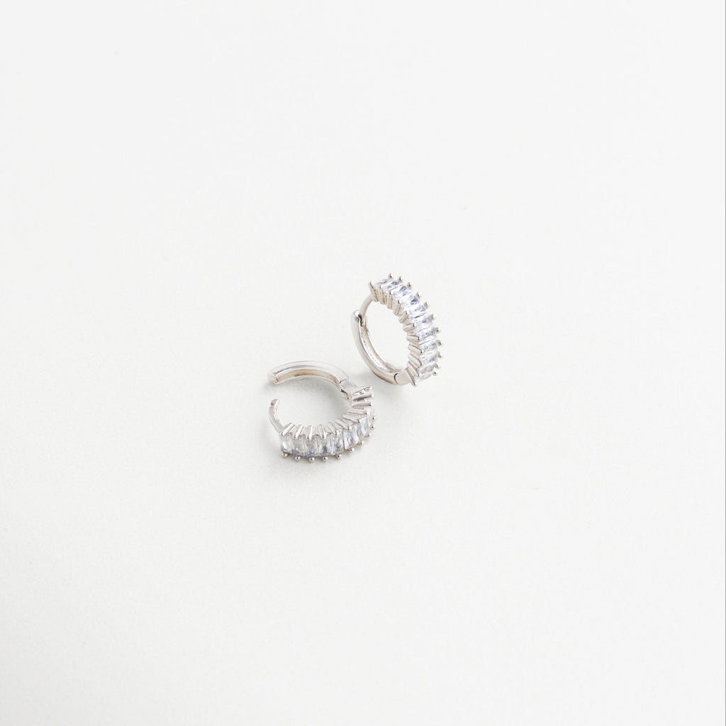 Arracadas finas con acabado brillante y zirconias visibles lateralmente, Aretes en ángulo con zirconias incrustadas y diseño pulido, Detalle en ángulo de arracadas elegantes con toque de brillo, Diseño lateral de arracadas con zirconias para uso diario