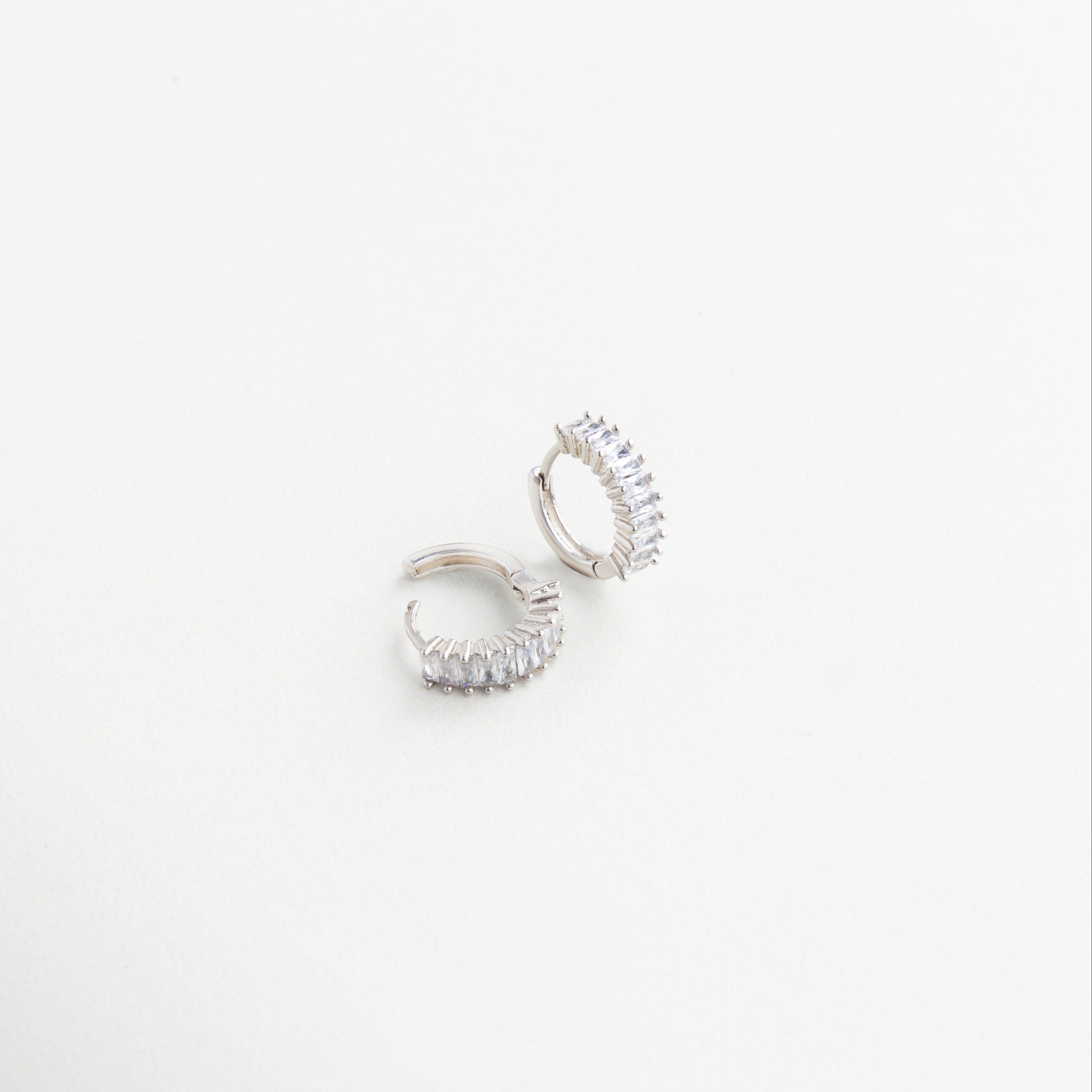 Arracadas finas con acabado brillante y zirconias visibles lateralmente, Aretes en ángulo con zirconias incrustadas y diseño pulido, Detalle en ángulo de arracadas elegantes con toque de brillo, Diseño lateral de arracadas con zirconias para uso diario