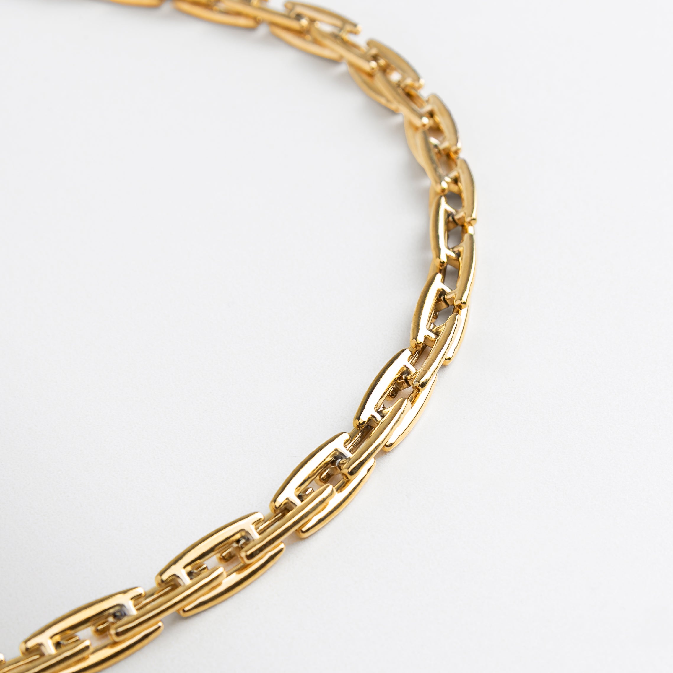 Collar Amelia Golden con volumen desde ángulo lateral, Diseño estructurado en dorado visto en perspectiva,Eslabones dorados con forma moderna en vista inclinada, Collar de acero con chapa de oro en ángulo decorativo