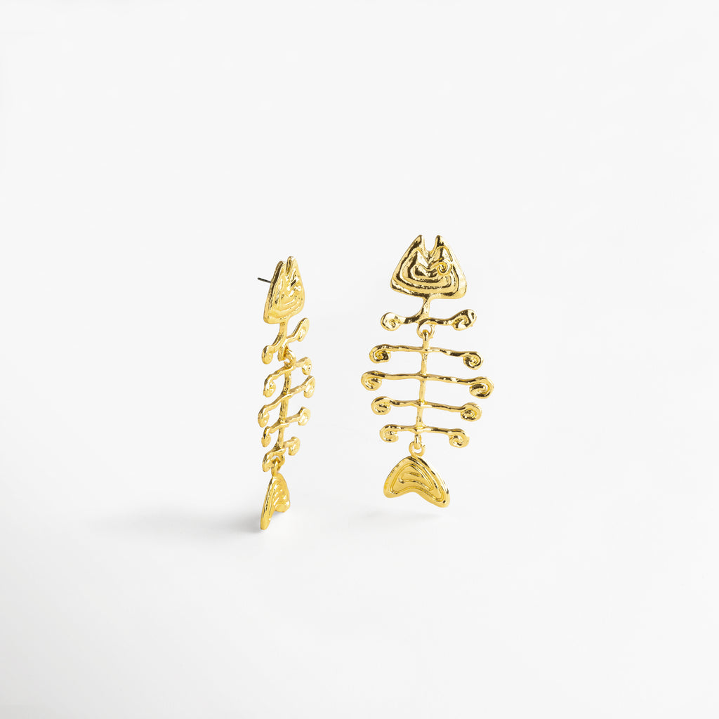 Perfil de aretes dorados con estructura de esqueleto, Diseño tridimensional en pendientes largos con silueta pez, Aretes con movimiento y forma angular vistos de lado, Detalle del contorno orgánico desde vista lateral