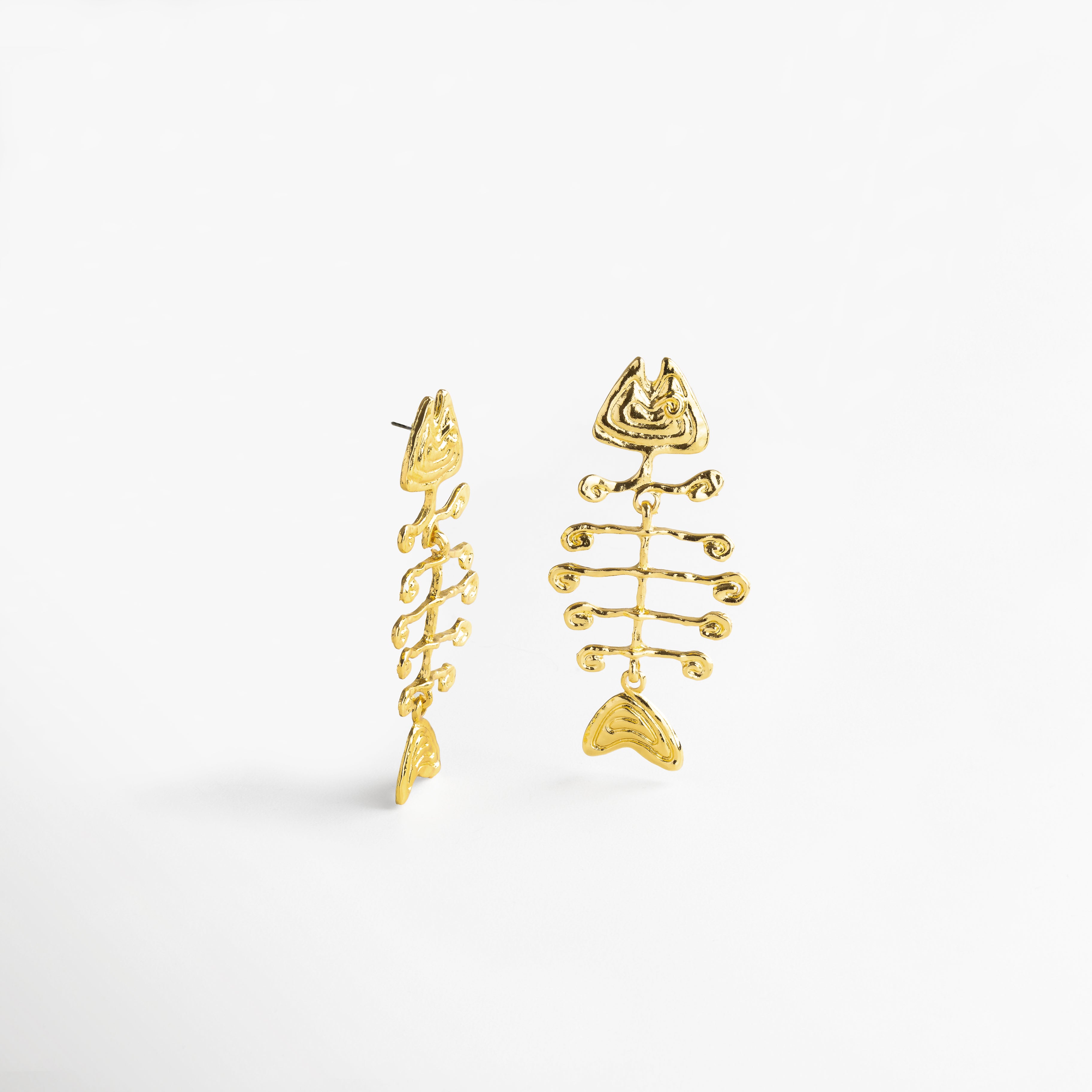 Perfil de aretes dorados con estructura de esqueleto, Diseño tridimensional en pendientes largos con silueta pez, Aretes con movimiento y forma angular vistos de lado, Detalle del contorno orgánico desde vista lateral