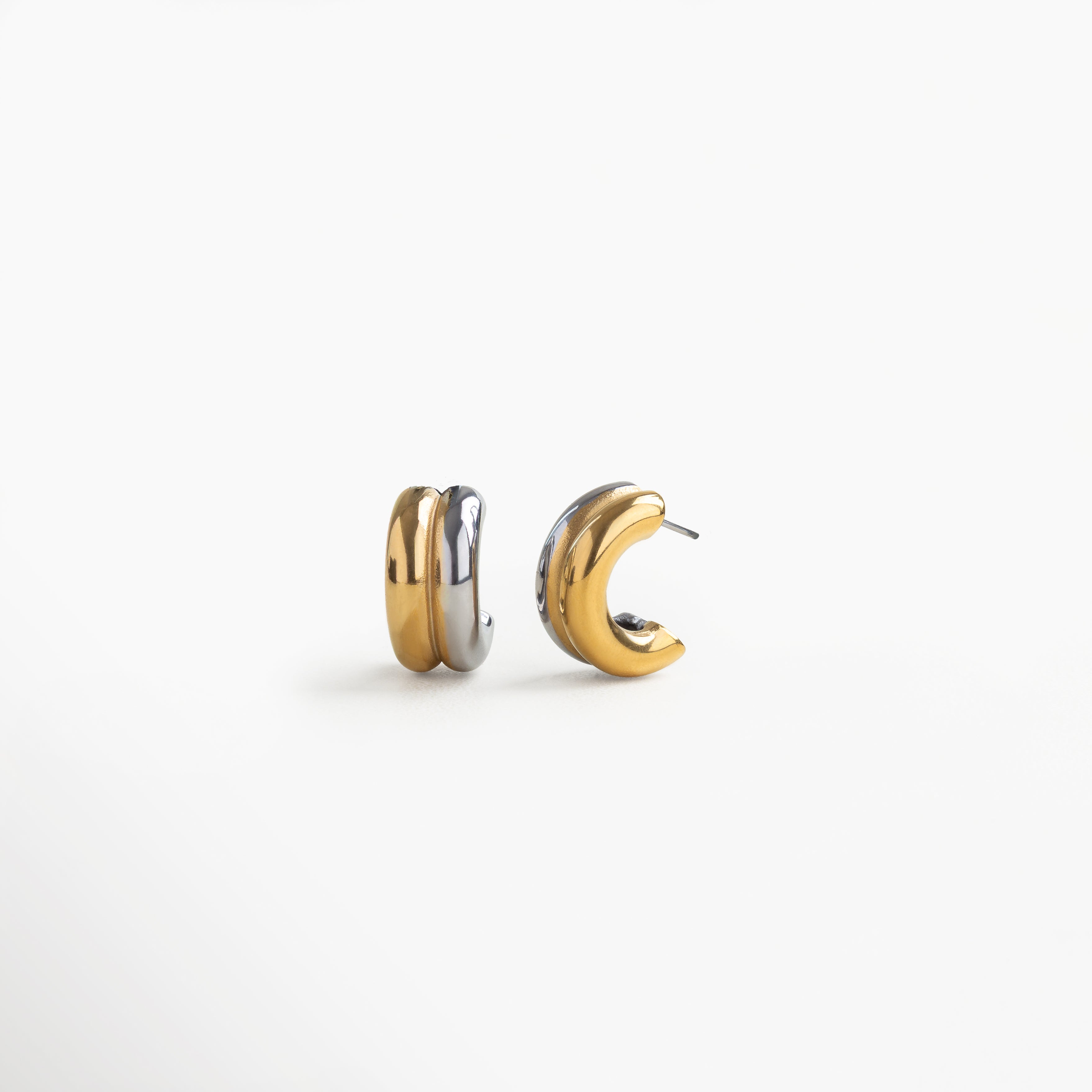Vista lateral de arracadas bicolor dorado y plateado con zirconia brillante, Perfil de aretes hoops bitono en acero inoxidable, diseño curvo con textura pulida, Aretes dorado-plateado con piedra de zirconia vistos desde un ángulo lateral, Detalle lateral de diseño moderno en arracadas bitono con acabado en acero brillante, Vista desde el lado de aretes hoops bitono con zirconia, estilo elegante y minimalista.