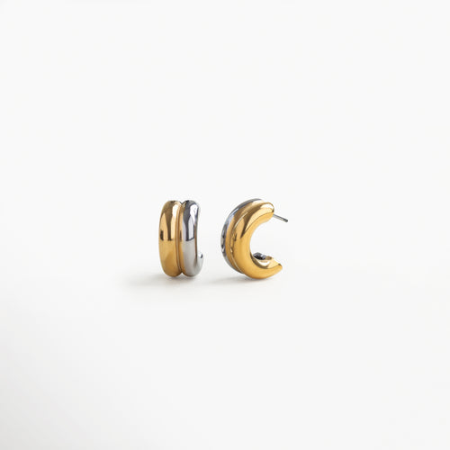 Vista lateral de arracadas bicolor dorado y plateado con zirconia brillante, Perfil de aretes hoops bitono en acero inoxidable, diseño curvo con textura pulida, Aretes dorado-plateado con piedra de zirconia vistos desde un ángulo lateral, Detalle lateral de diseño moderno en arracadas bitono con acabado en acero brillante, Vista desde el lado de aretes hoops bitono con zirconia, estilo elegante y minimalista.