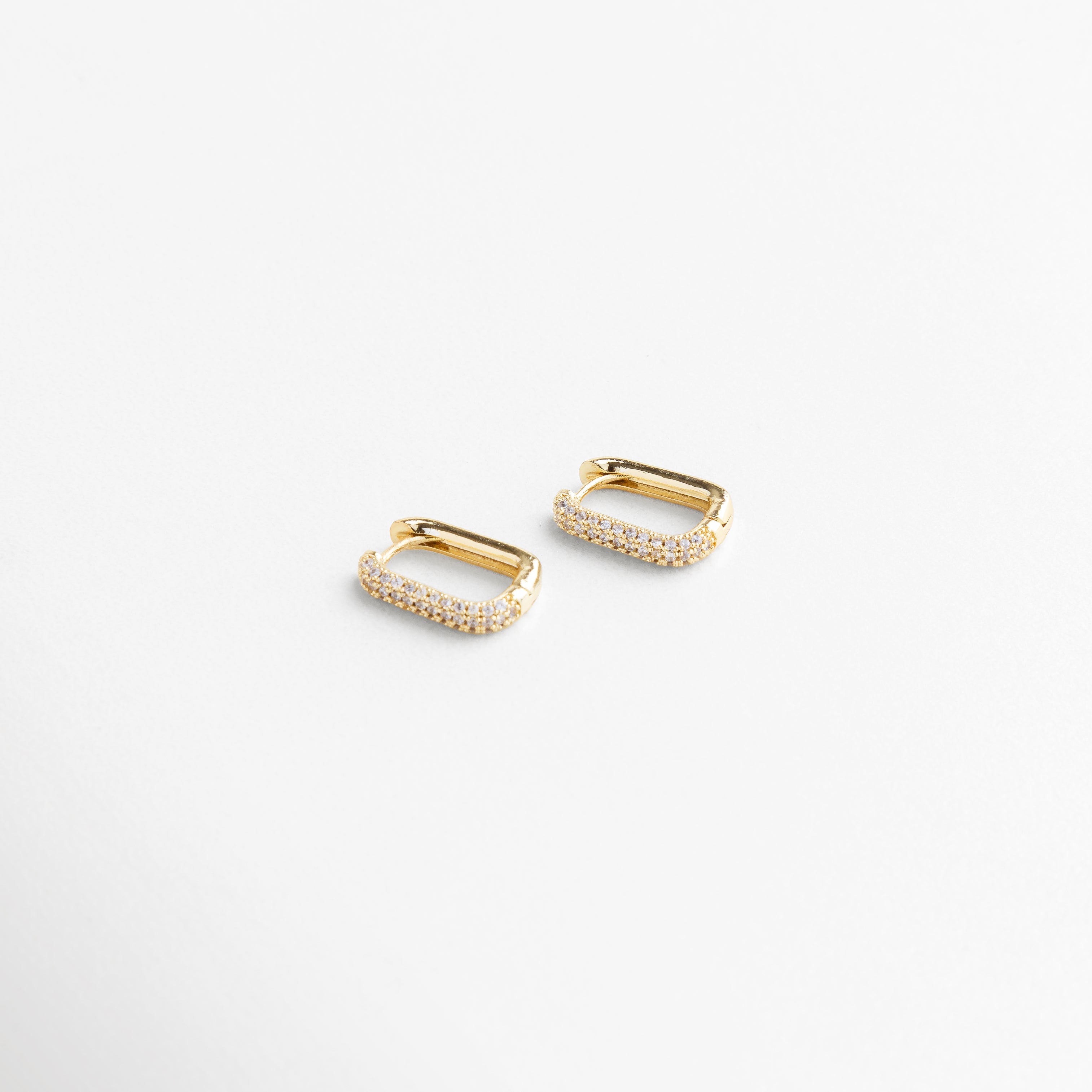 textura suave y uniforme del aro dorado, contraste entre metal pulido y zirconias, diseño atemporal y refinado, joya de alta calidad con terminados impecables, estilo minimalista y elegante