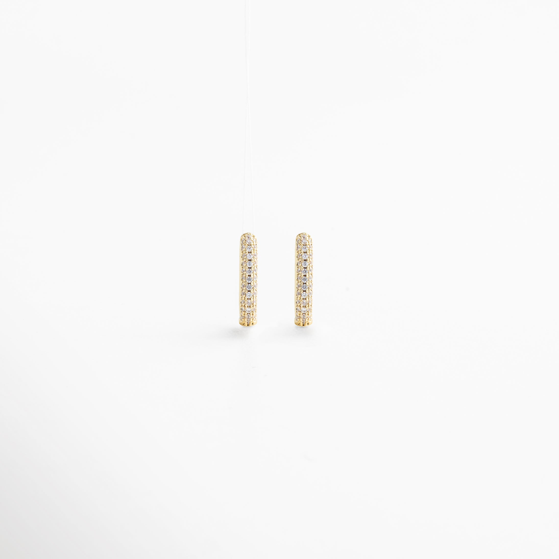 acercamiento a las zirconias en los mini hoops, corte preciso y destellos delicados, engaste simétrico y pulido, acabado dorado brillante, detalle lujoso y contemporáneo