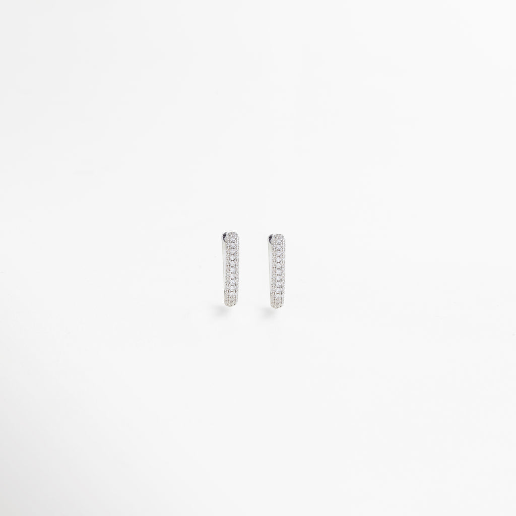 Vista frontal de aretes pequeños rectangulares en oro blanco con incrustaciones de zirconias, perfectos para un estilo sofisticado y versátil.