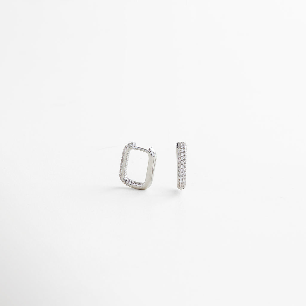 Aretes rectangulares de oro blanco con zirconias vistos de lado, mostrando su silueta geométrica y acabado brillante.