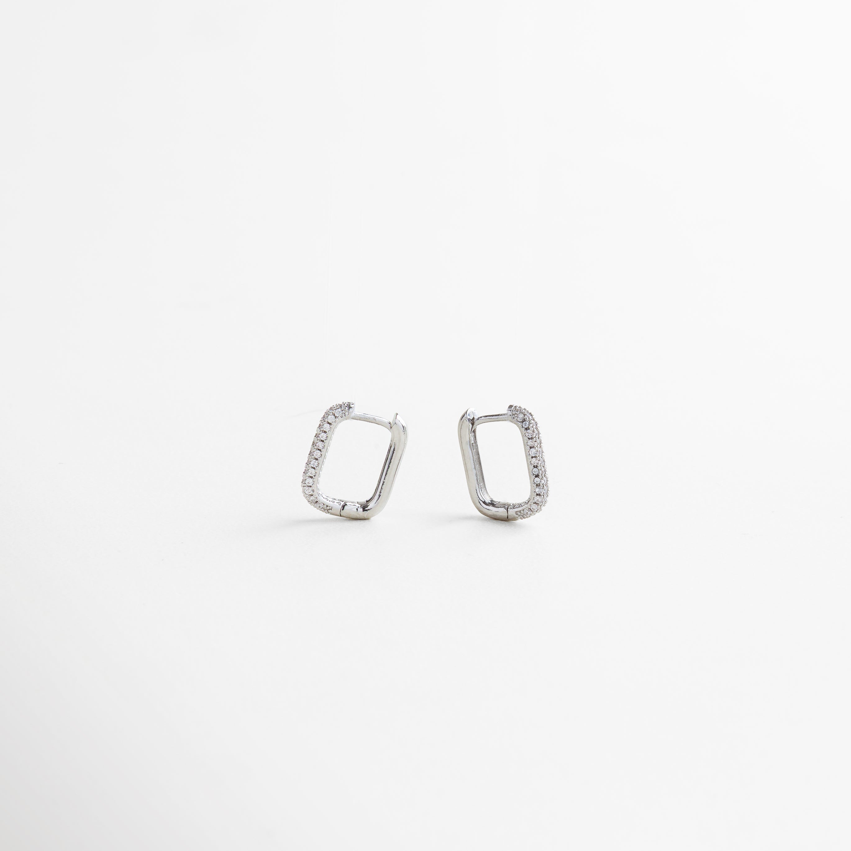 Aretes rectangulares en oro blanco con zirconias brillantes, diseño geométrico minimalista para un look moderno y elegante.