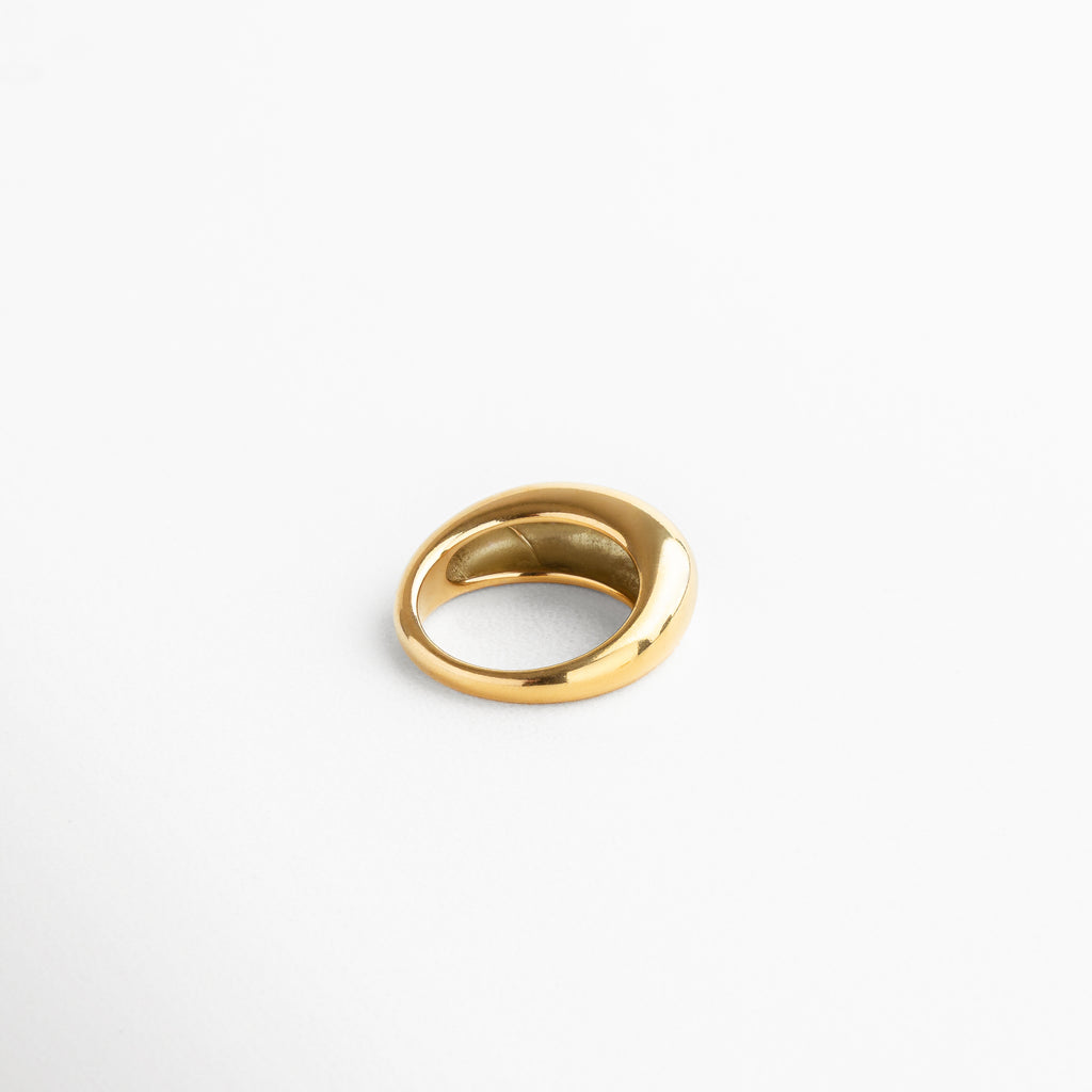 Vista superior del anillo Katerina Golden, mostrando la parte más alta de 7 mm y su forma contemporánea. Anillo Katerina Golden capturado desde arriba, resaltando su volumen y superficie dorada pulida. Toma cenital del anillo en acero inoxidable con chapa de oro, ideal para lucir en combinaciones de joyería. Anillo dorado Katerina Golden desde vista superior, destacando su diseño bold y elegante.Perspectiva superior del anillo Katerina, con acabado en oro de 18K y líneas curvas sofisticadas