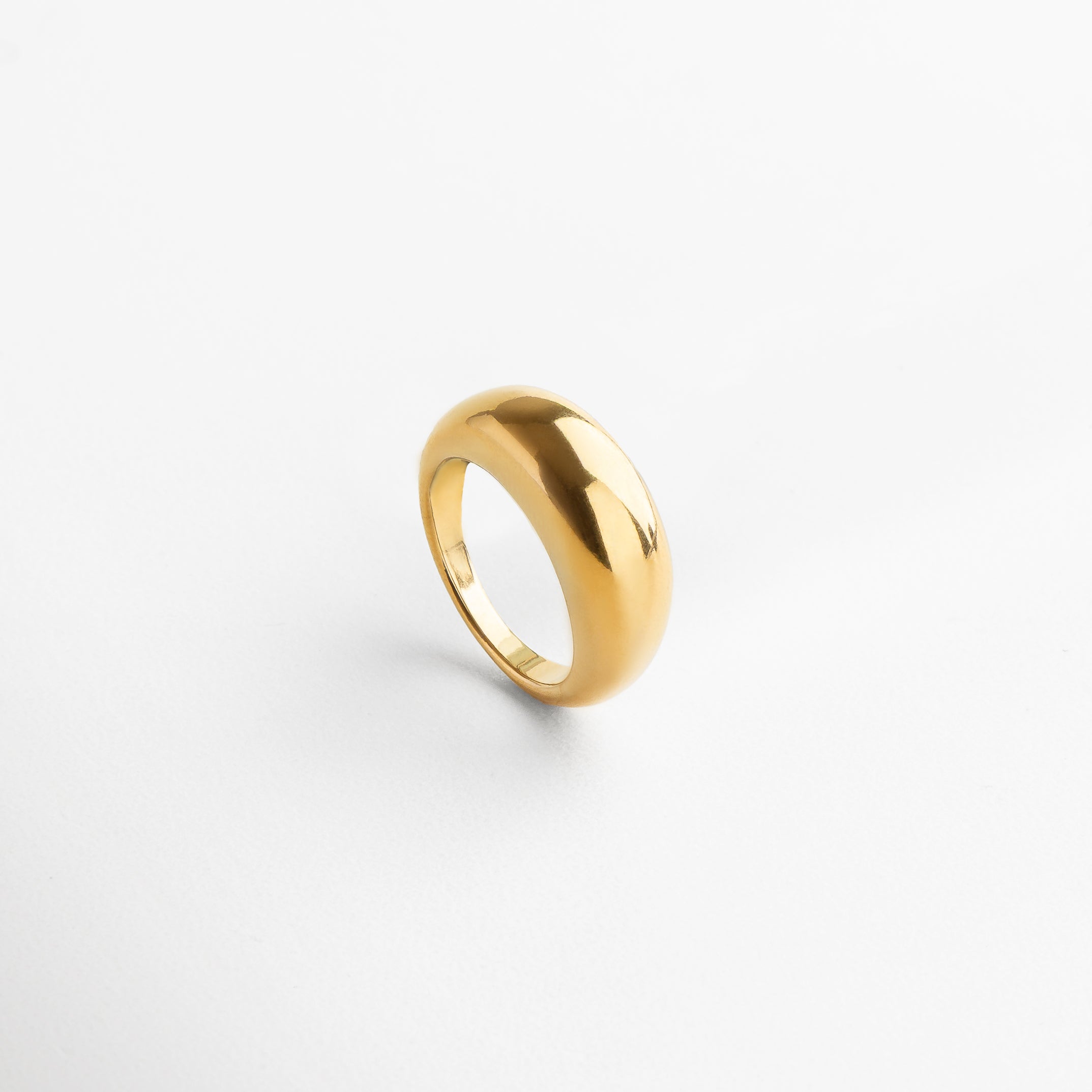 Anillo Katerina Golden visto desde el frente, mostrando su diseño voluminoso y elegante en acero inoxidable con chapa de oro de 18K.Vista frontal del anillo Katerina Golden, con acabado brillante y silueta moderna que destaca por su forma audaz.
Anillo dorado de acero inoxidable desde el ángulo frontal, resaltando su grosor de 5 mm y estilo statement.Diseño moderno del anillo Katerina Golden, con un acabado dorado pulido y estructura sólida visto desde el frente. Primer plano del anillo Ka